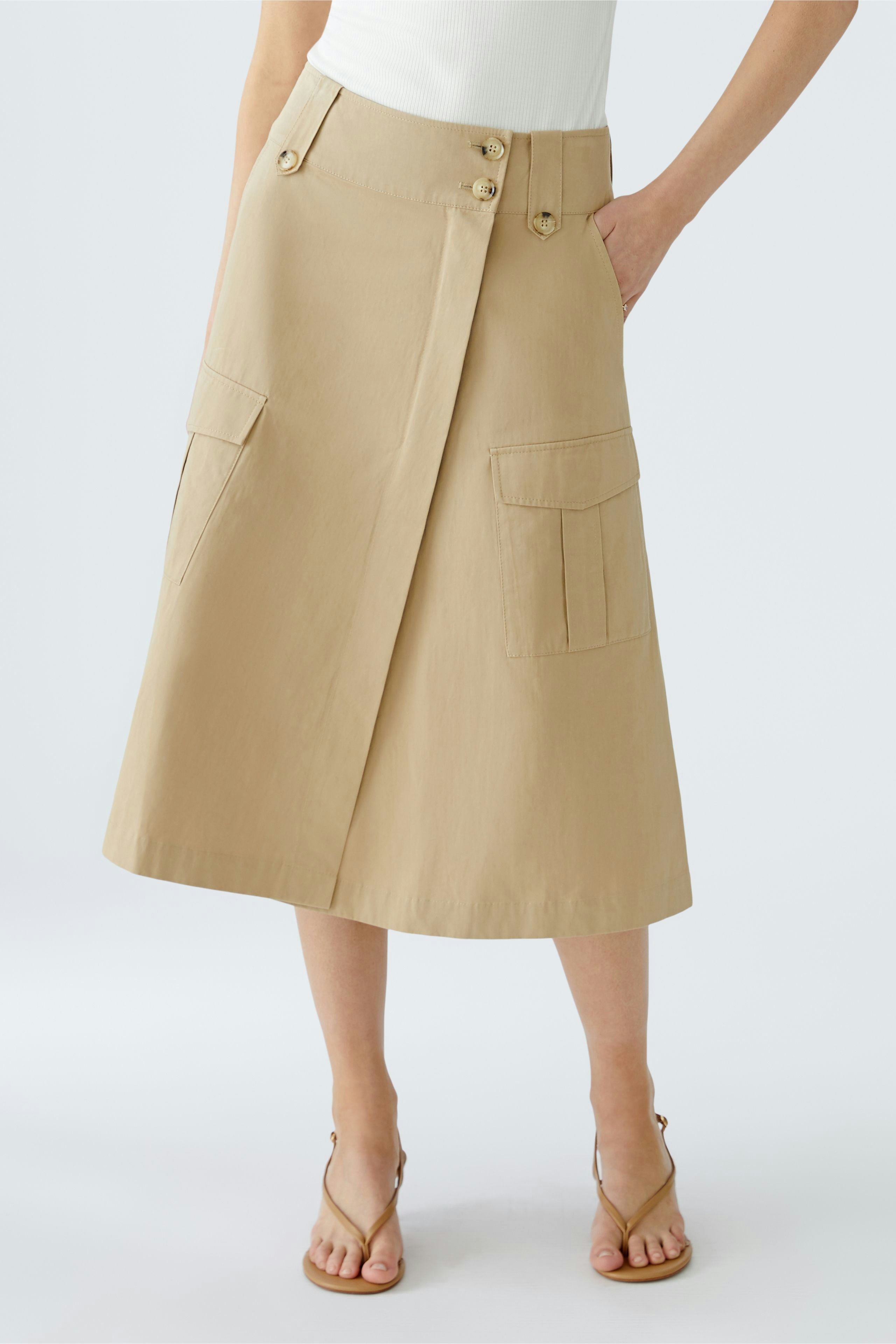 Chic wrap skirt: A woman in a beige wrap skirt with pockets, styled for a modern look.