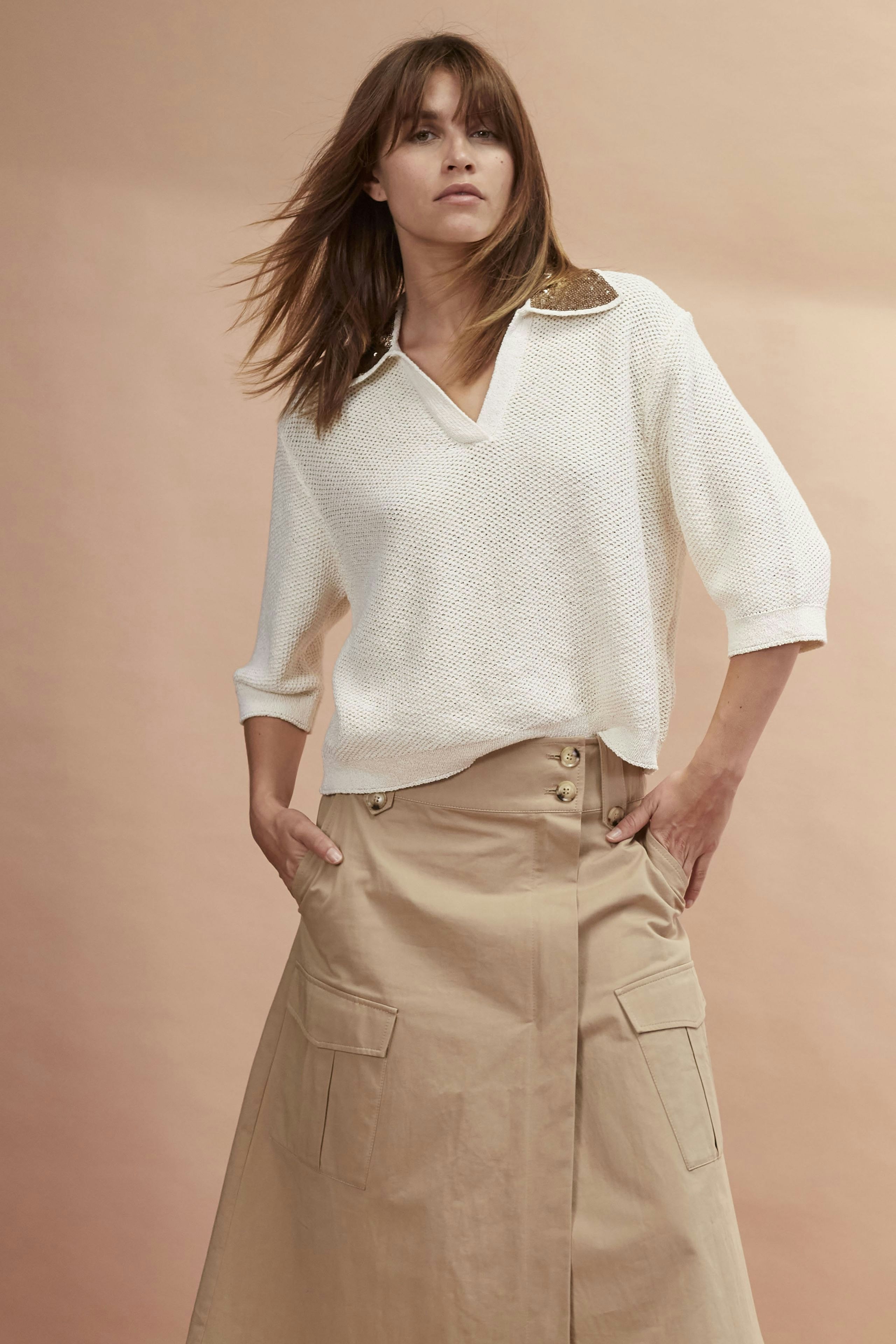 Chic wrap skirt: Confident woman in a stylish beige wrap skirt with pockets.
