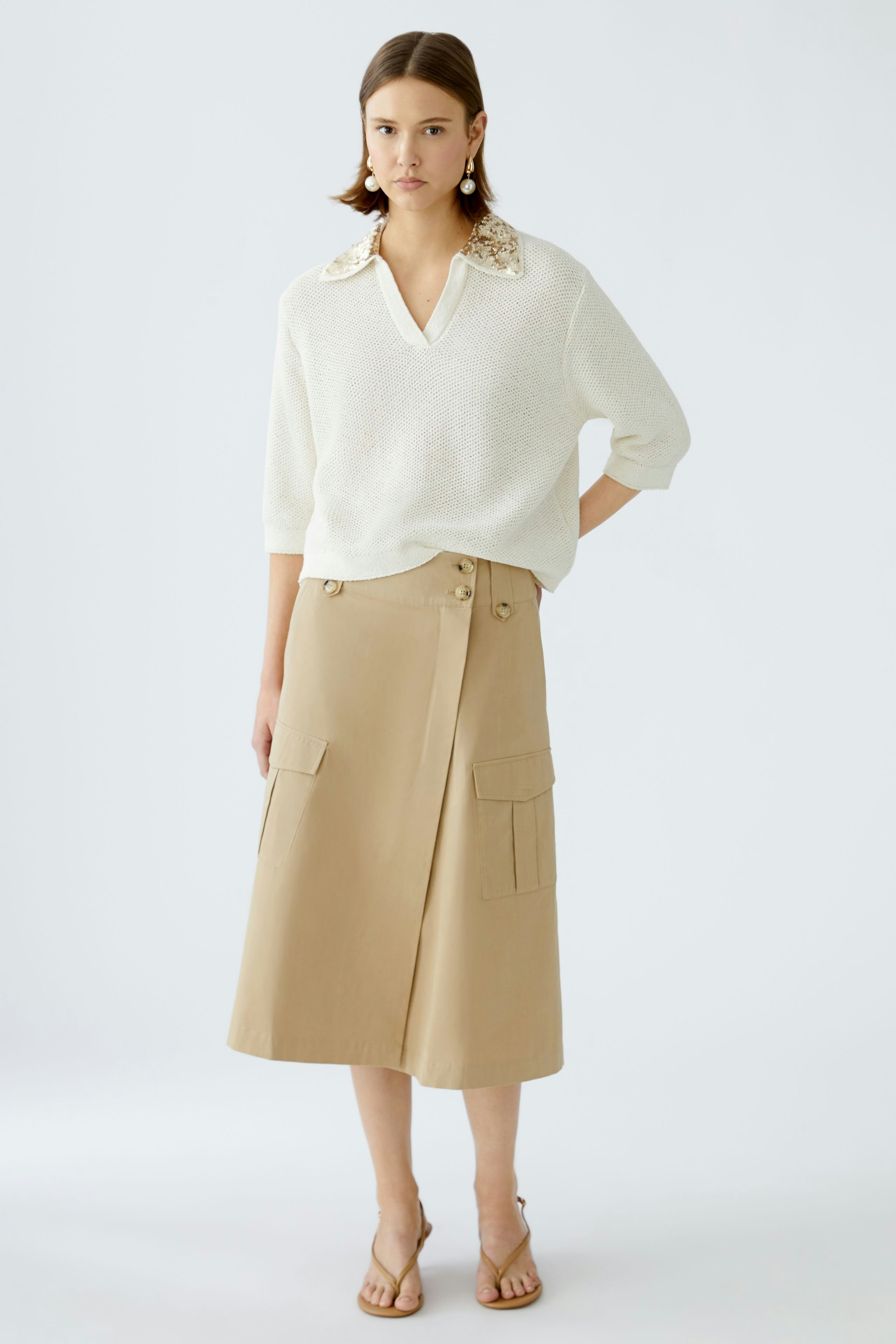 Chic wrap skirt: A woman in a stylish beige wrap skirt with pockets, paired with a light pullover.