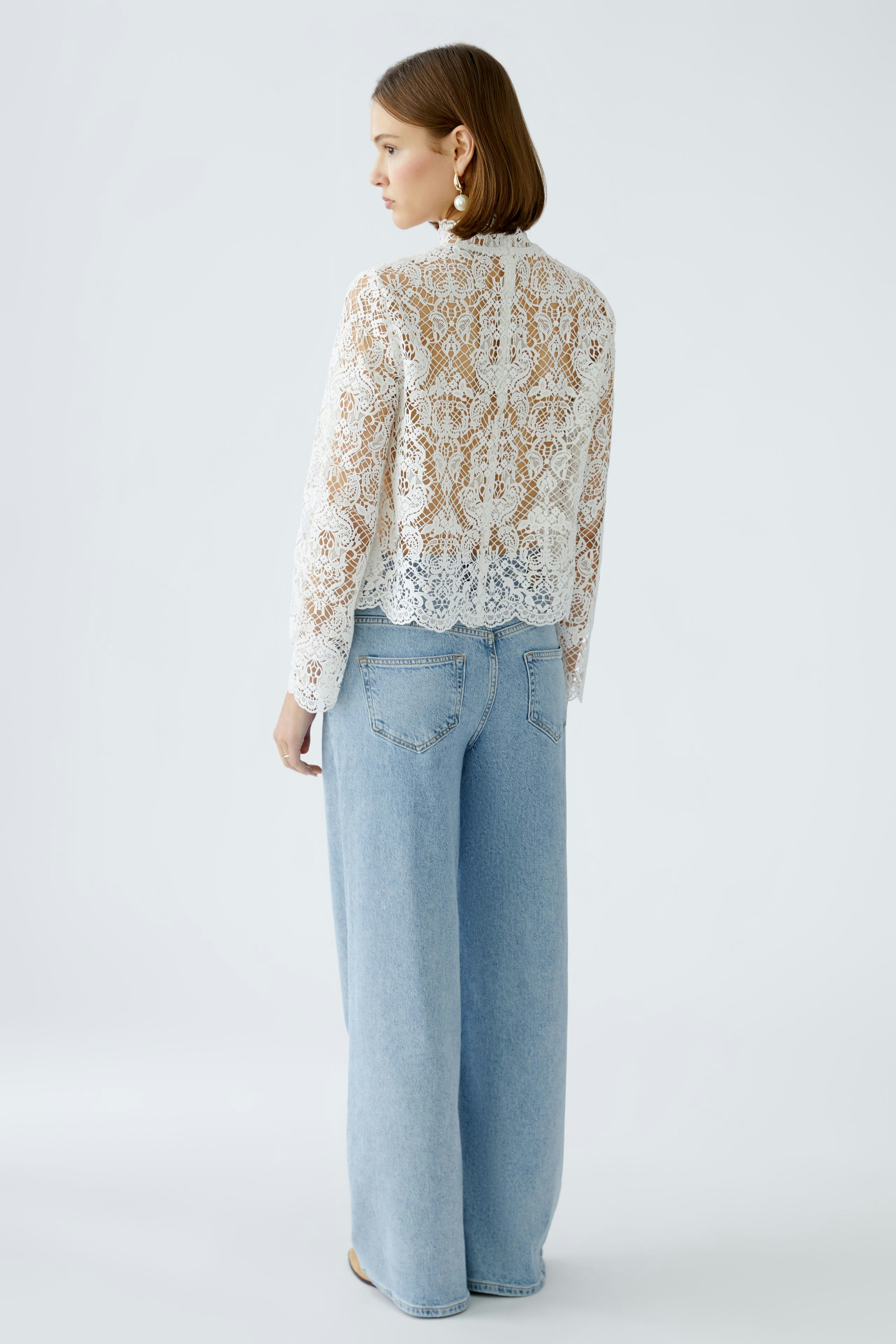 Elegant women's blouse: A woman in a delicate lace blouse paired with wide-leg jeans.