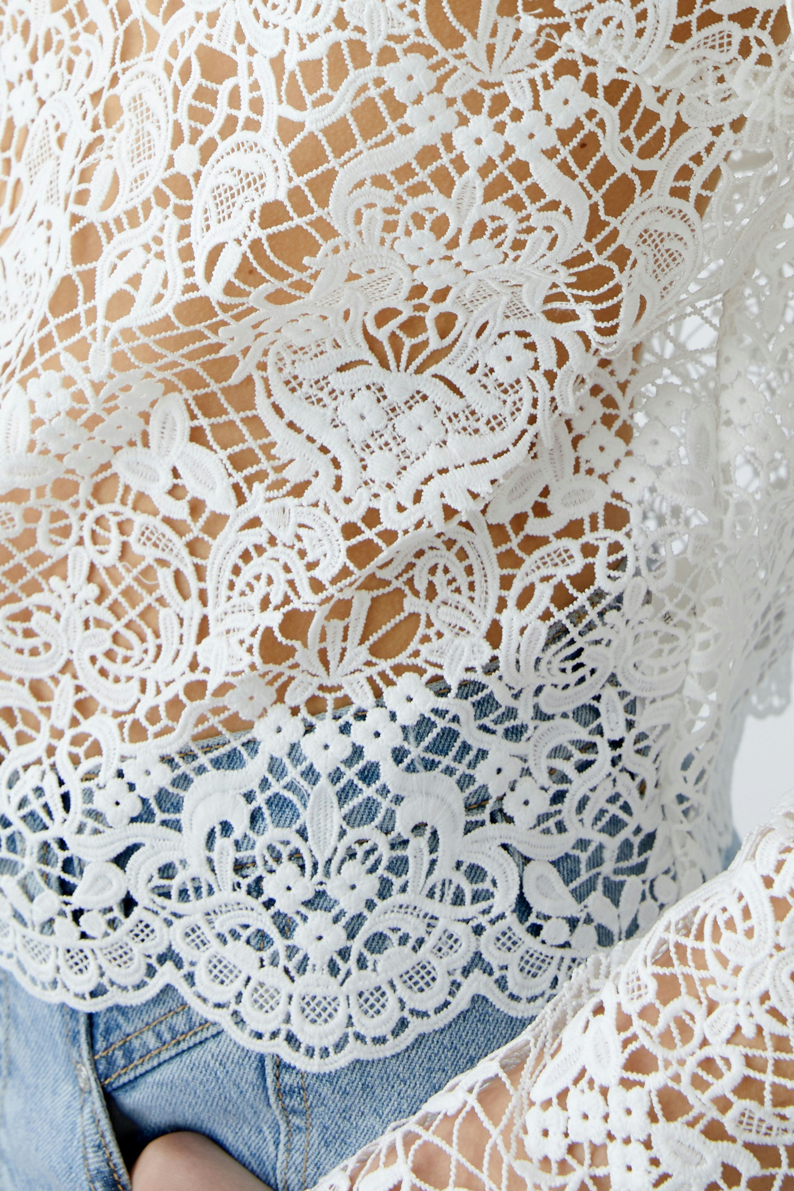 Elegant women's blouse: A woman in a delicate white lace blouse paired with denim shorts.