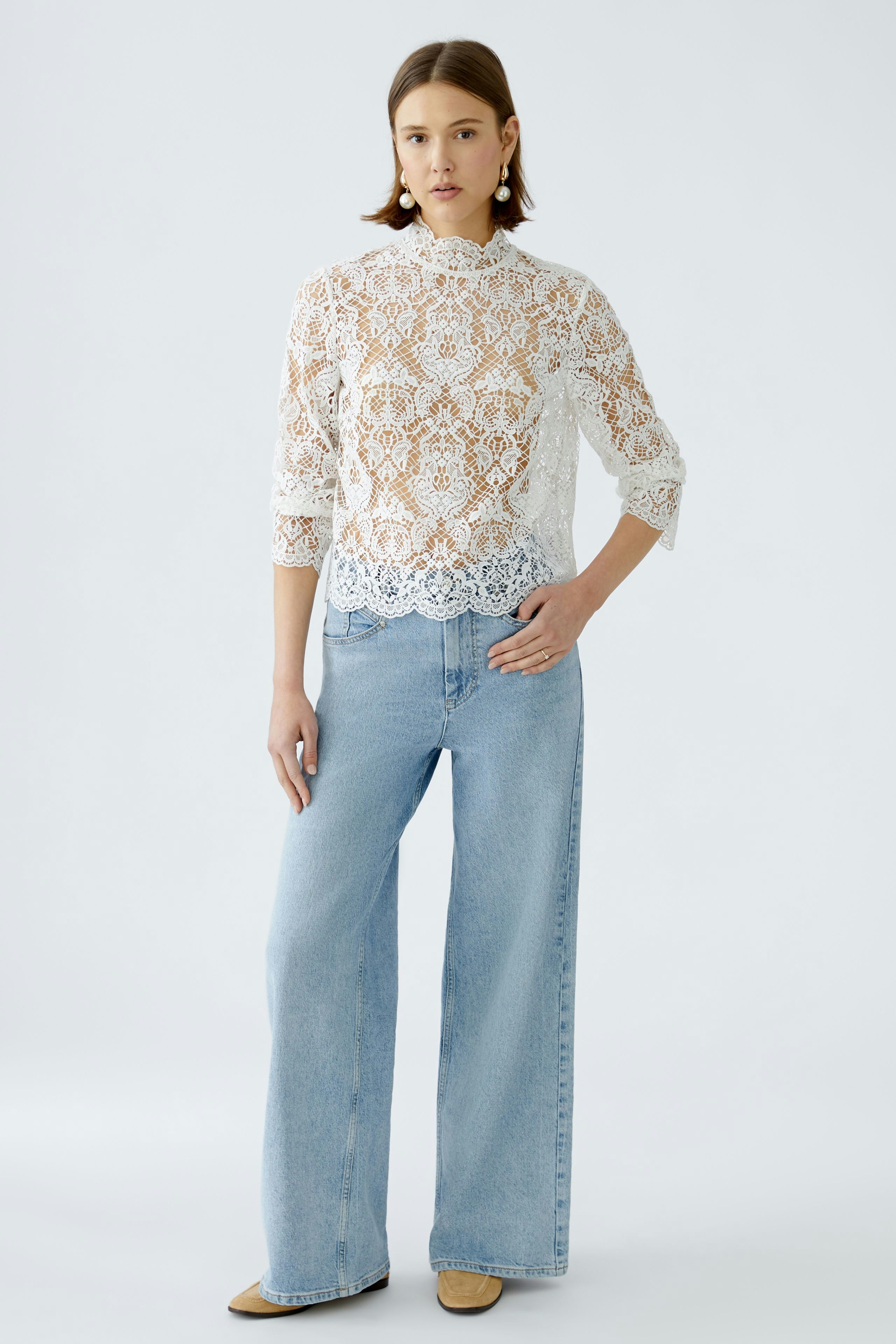 Elegant women's blouse: A woman in a white lace blouse paired with light blue jeans.