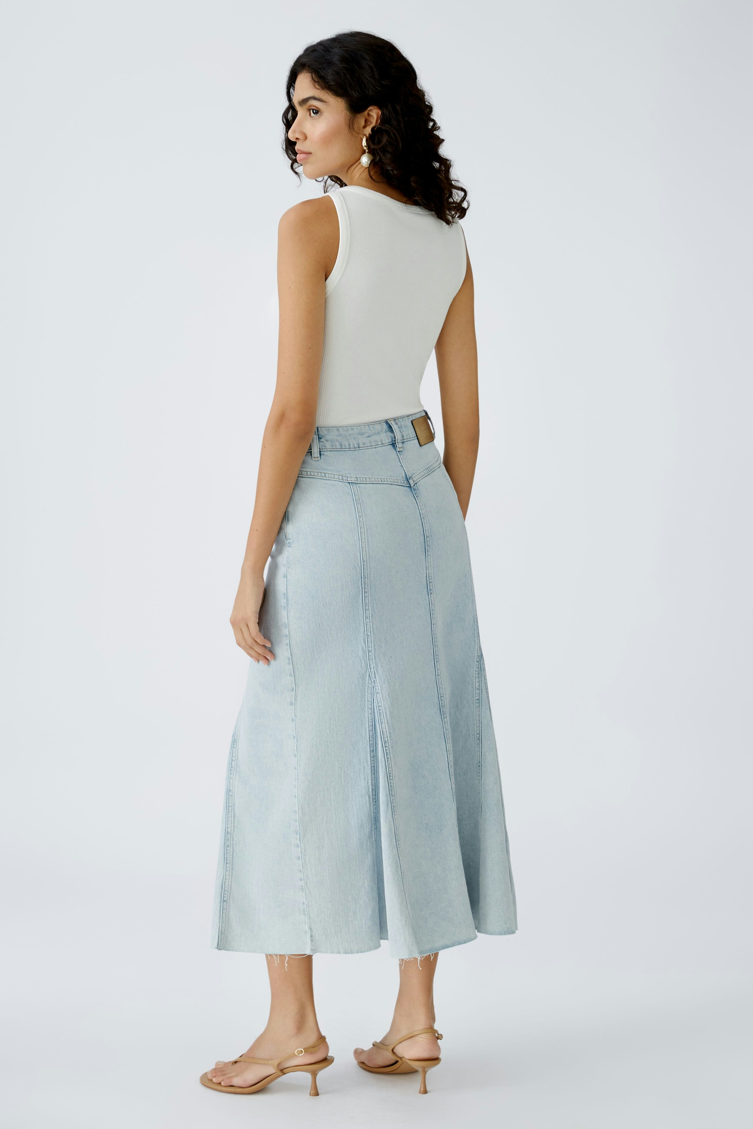 Stylish denim skirt: Woman in a light blue long denim skirt with a fitted top, showcasing a modern look.
