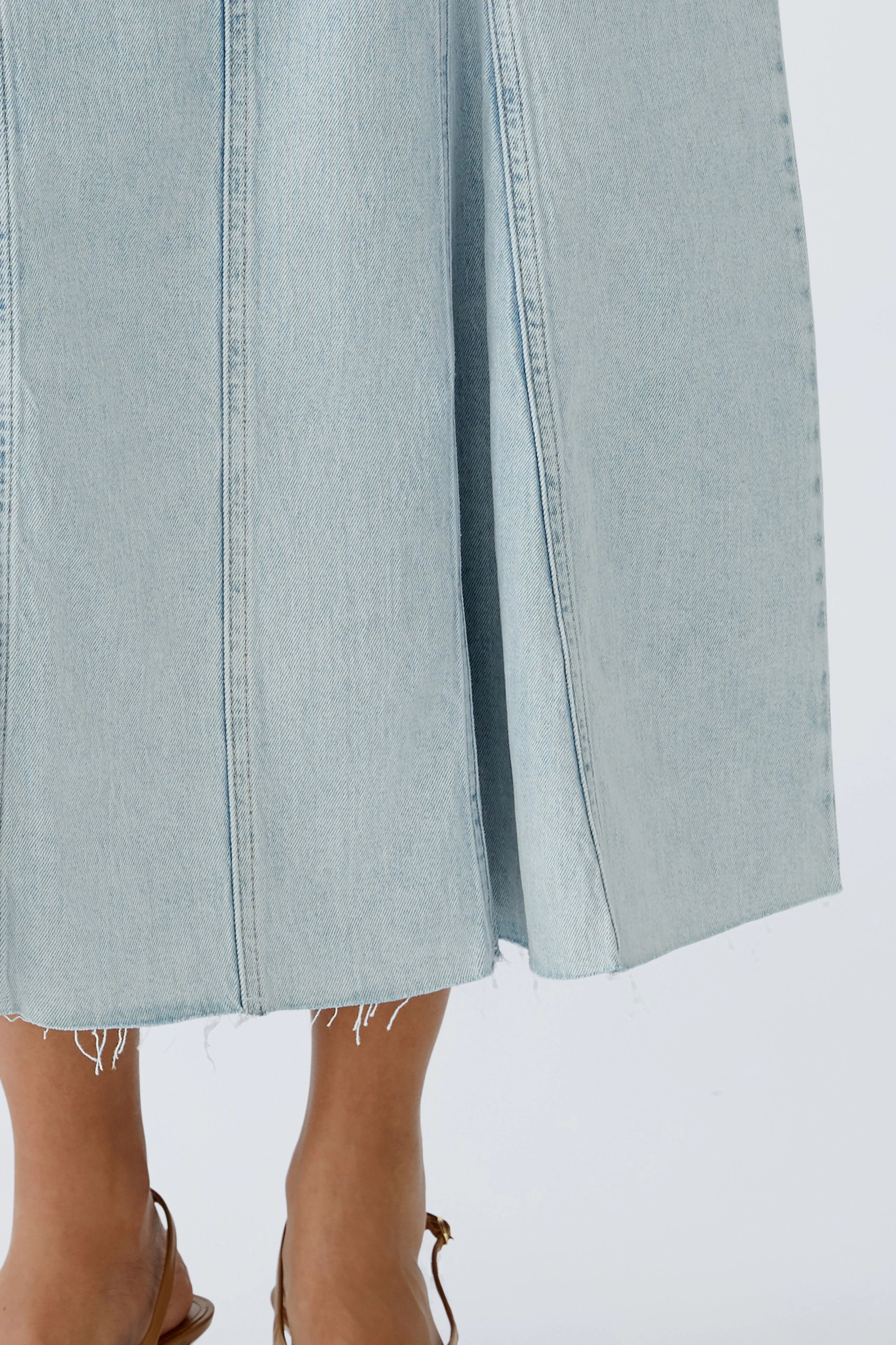 Eleganter Jeansrock: Frau trägt einen hellblauen Jeansrock mit lässigem Schnitt und fransigem Saum.
