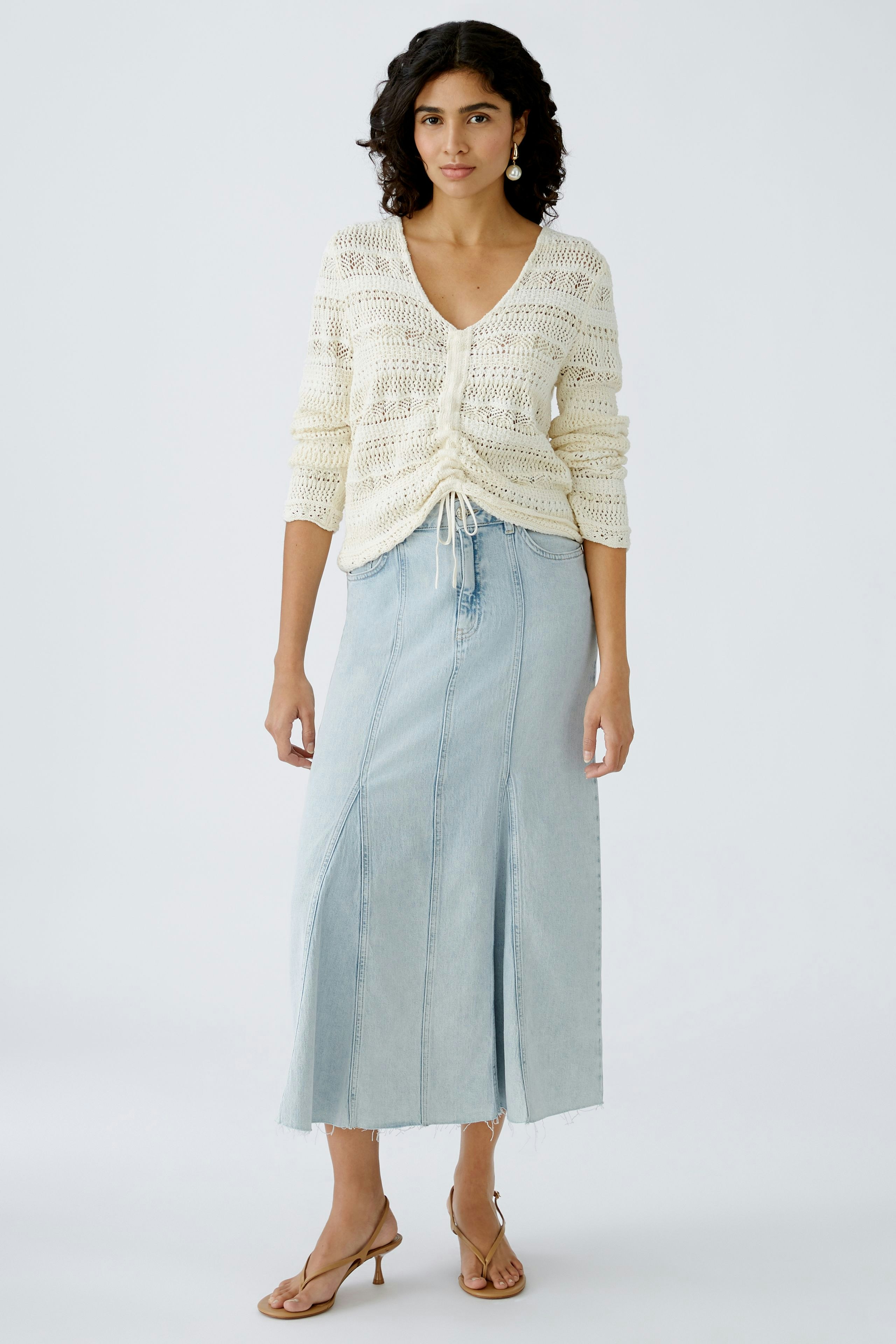 Stylish denim skirt: Woman in a light blue long skirt with a front slit, paired with a casual pullover.
