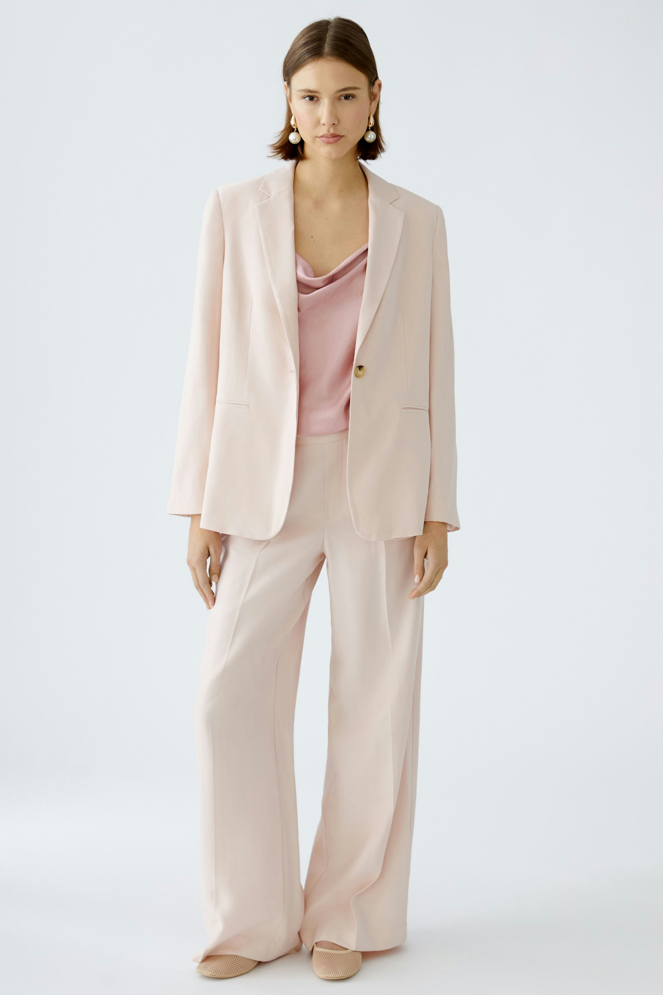 Eleganter Blazer: Frau in zartem Blazer, kombiniert mit einem schlichten Top und weiten Hosen.