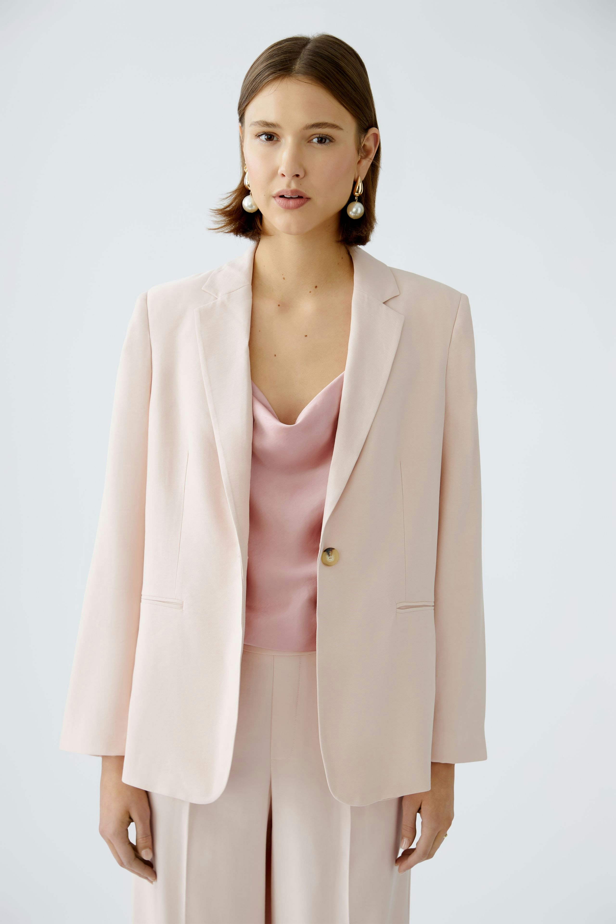 Eleganter Damen-Blazer in zartem Rosa, kombiniert mit einem schlichten Top, für einen modernen Look.
