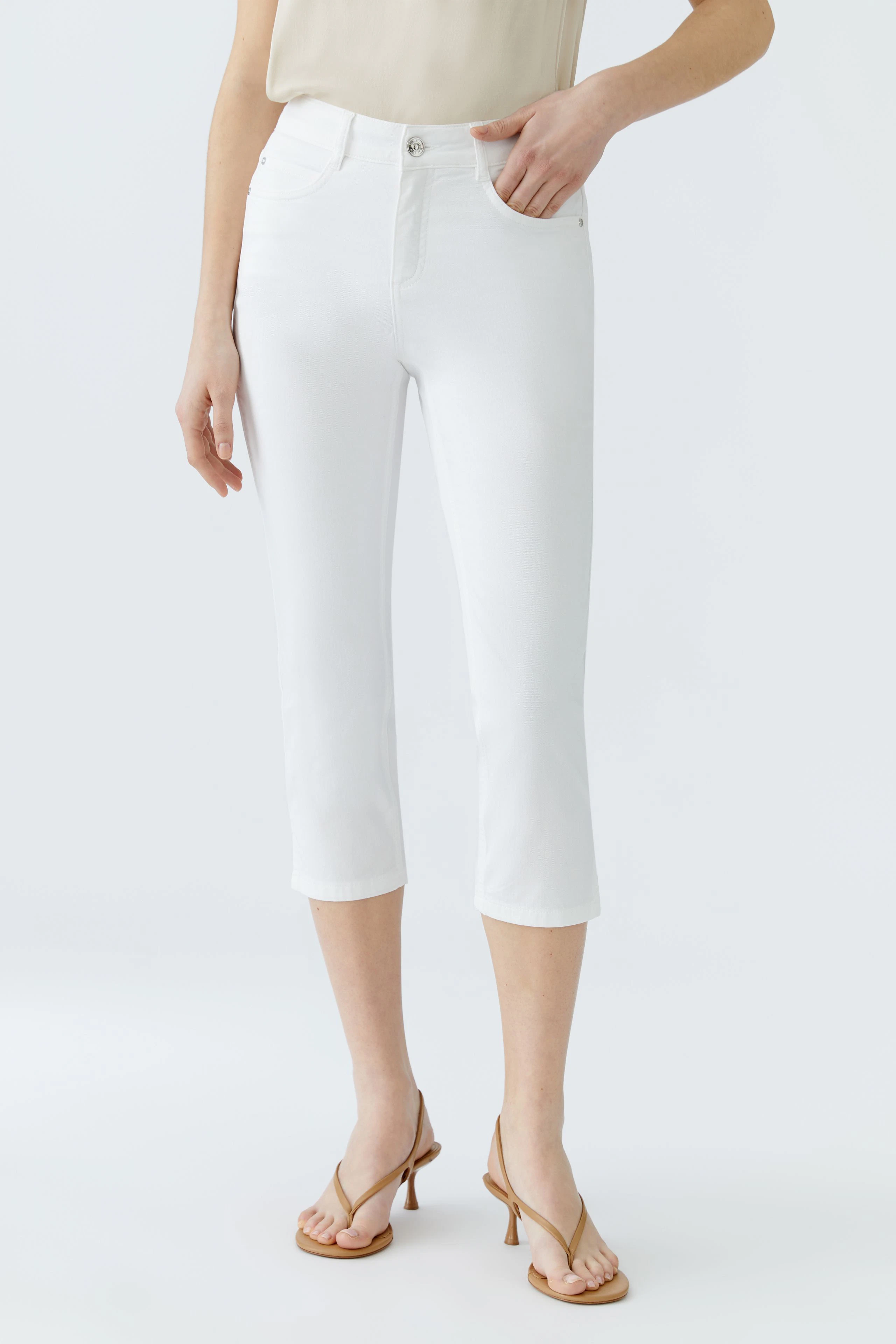 Elegante Damen-Hose: Frau in weißen, knöchellangen Jeans mit lässigem Oberteil und Sandalen.