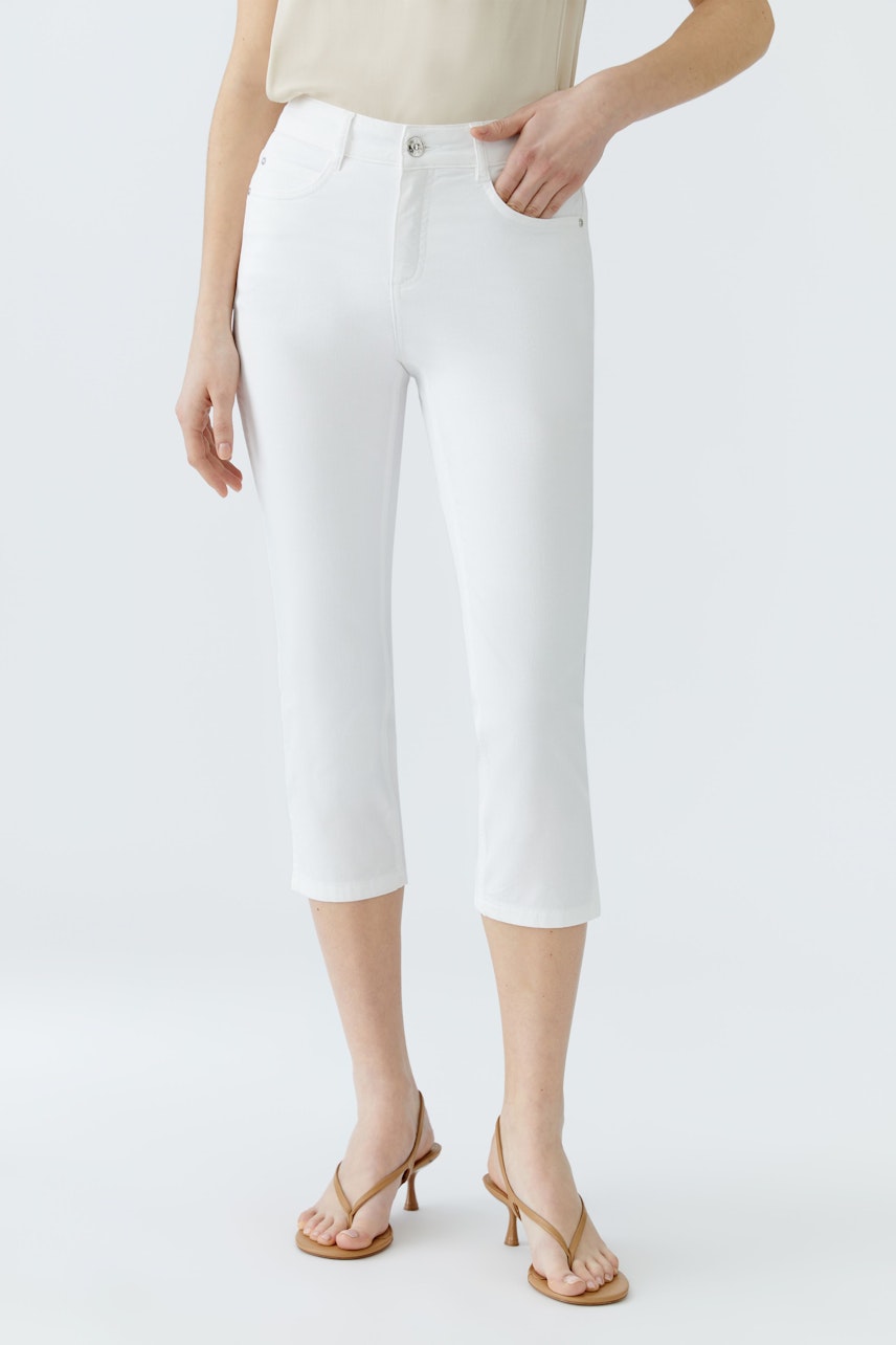 Stylish women's cropped pants: A woman in white pants, perfect for a chic summer look.