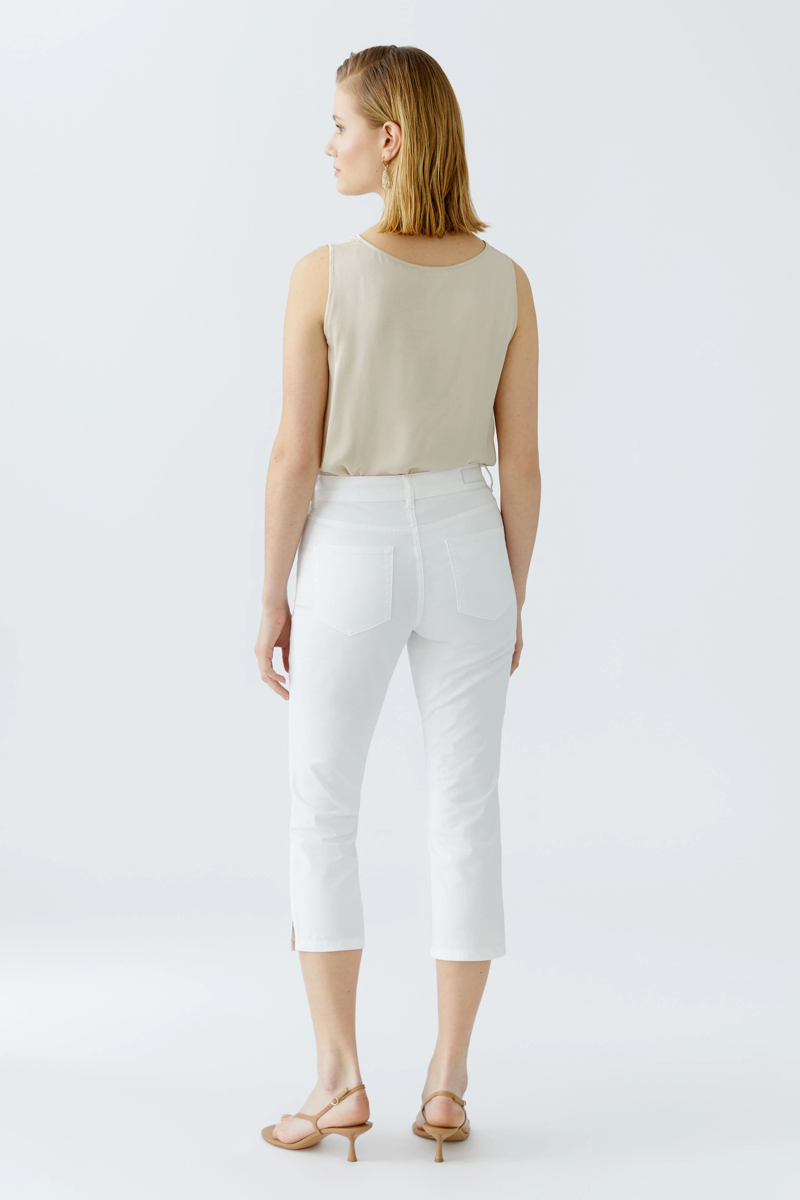 Elegante Damen-Hose: Frau in weißer, knöchellanger Hose mit seitlichen Schlitzen, lässig und modern.