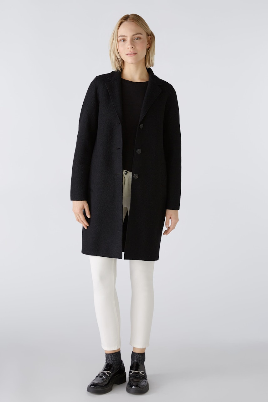 Elegant women's coat: A woman in a black coat with buttons, paired with light pants, exudes sophistication.