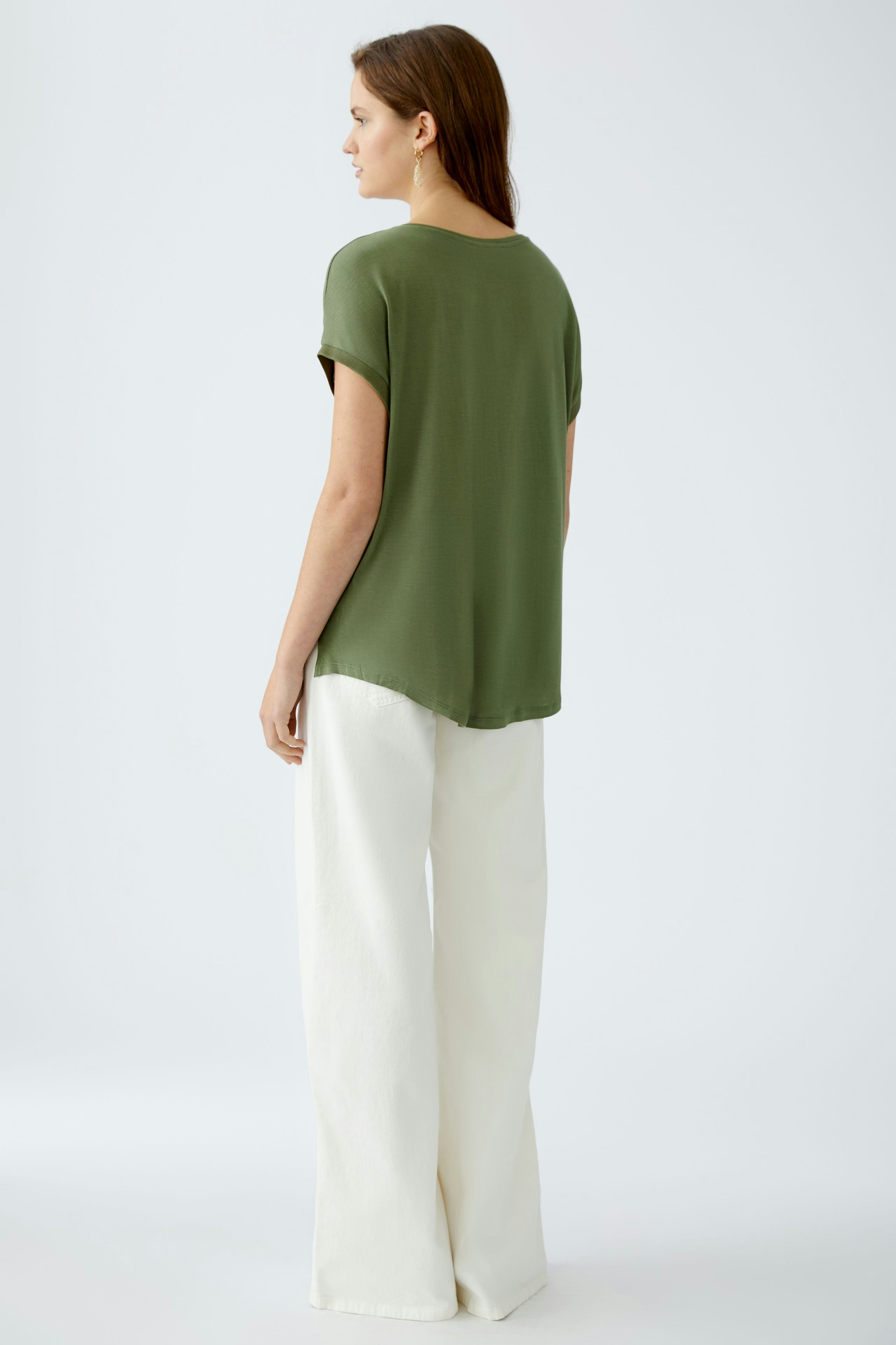 Bequemes Blusenshirt: Frau trägt ein olivgrünes, lässiges Shirt mit kurzen Ärmeln und weitem Schnitt.