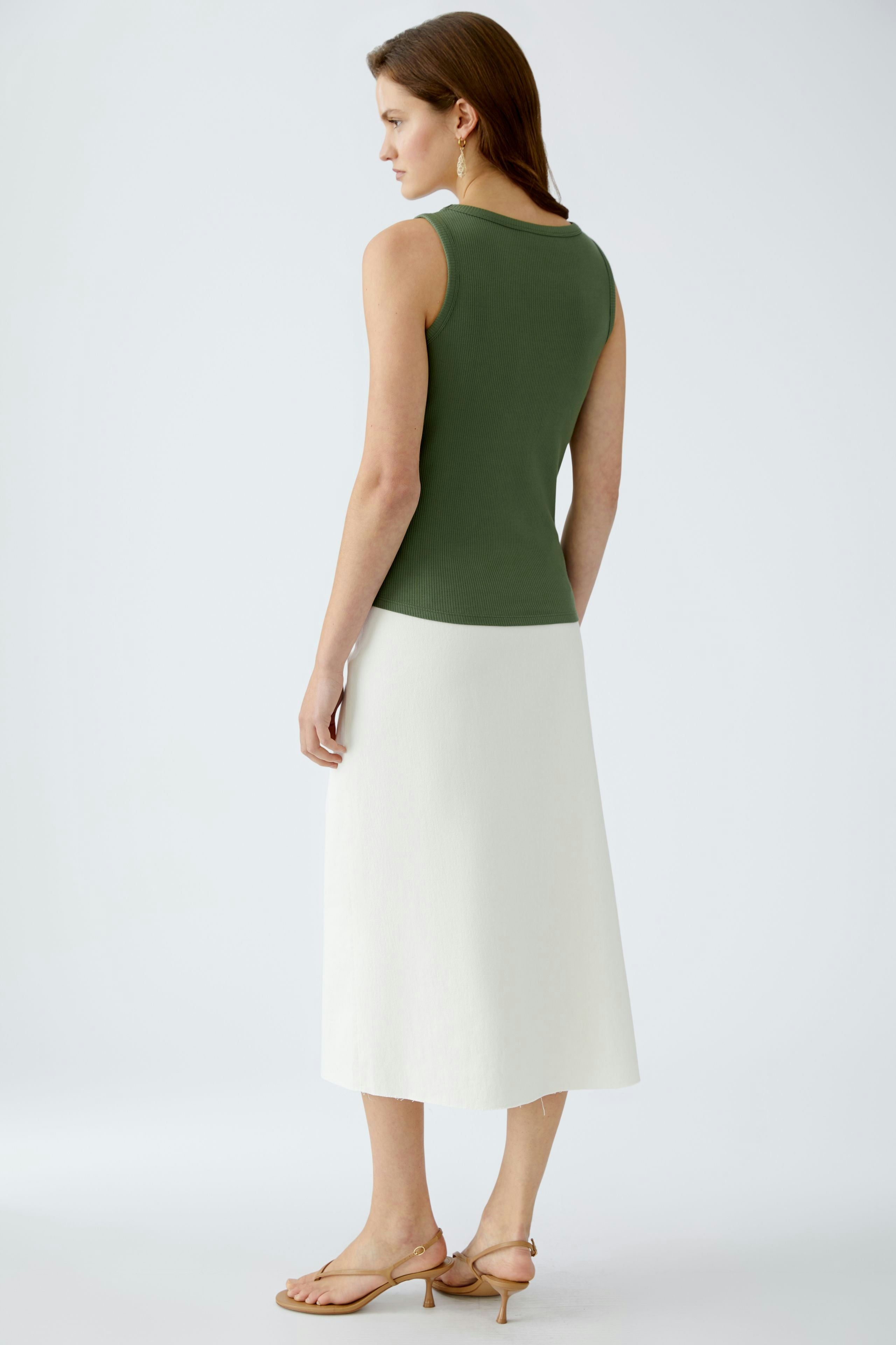 Stylish women's top: A woman in a fitted green top paired with a flowing white skirt.