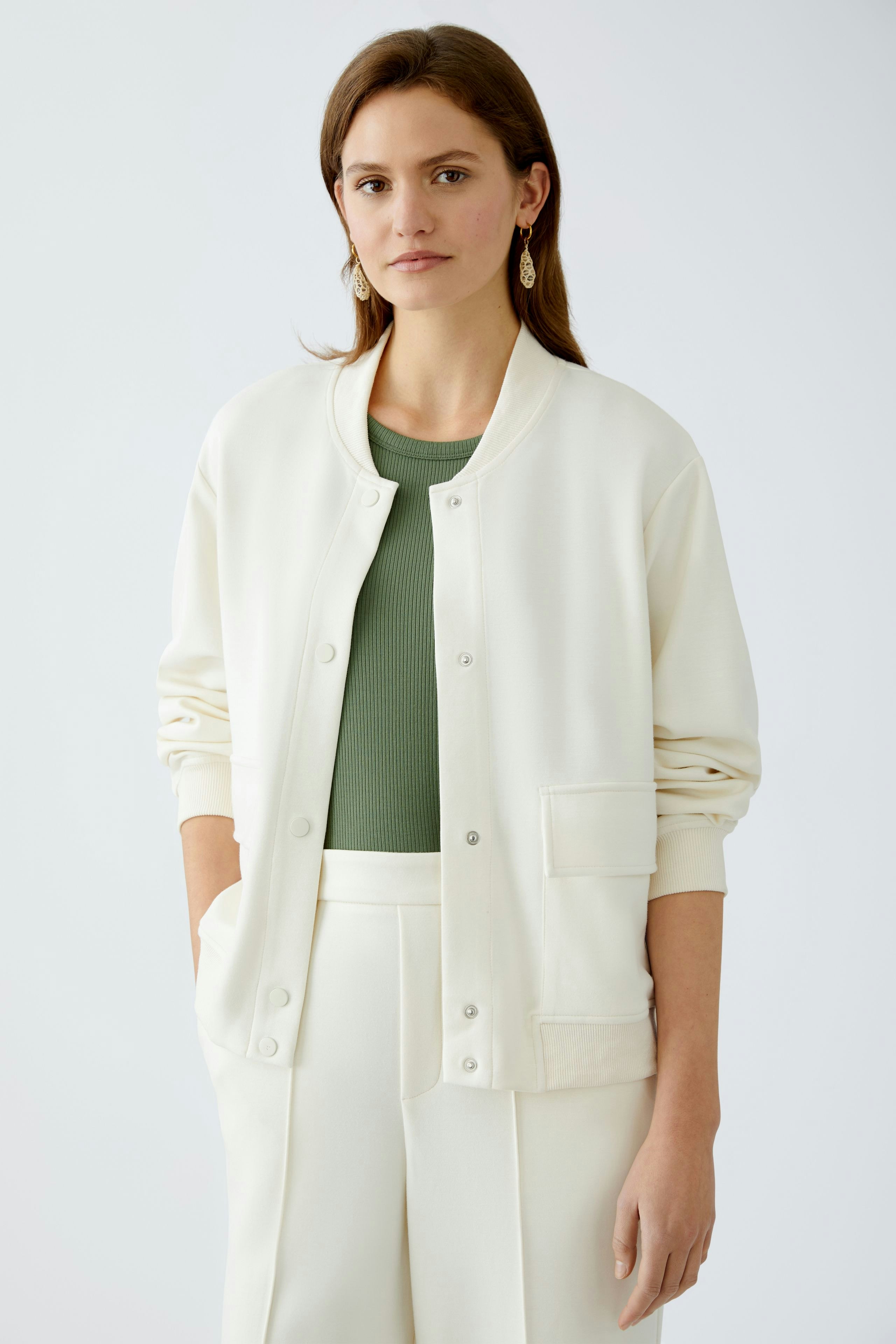 Damen-Blouson: Frau in weißem Blouson mit grünem Oberteil und eleganter Hose, lässiger Look.