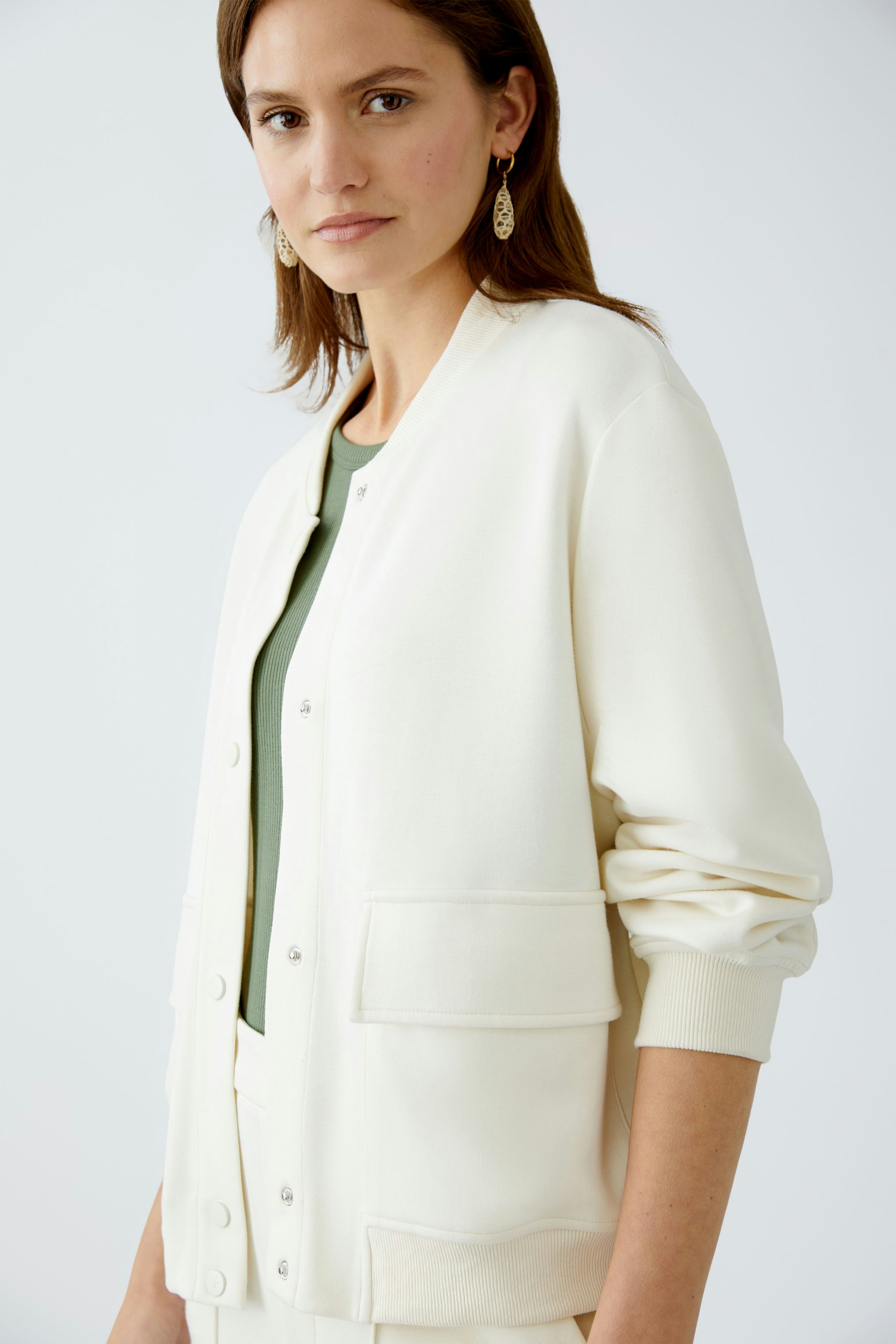 Eleganter Blouson: Junge Frau in cremefarbener Bomberjacke mit praktischen Taschen und sportlichem Schnitt.