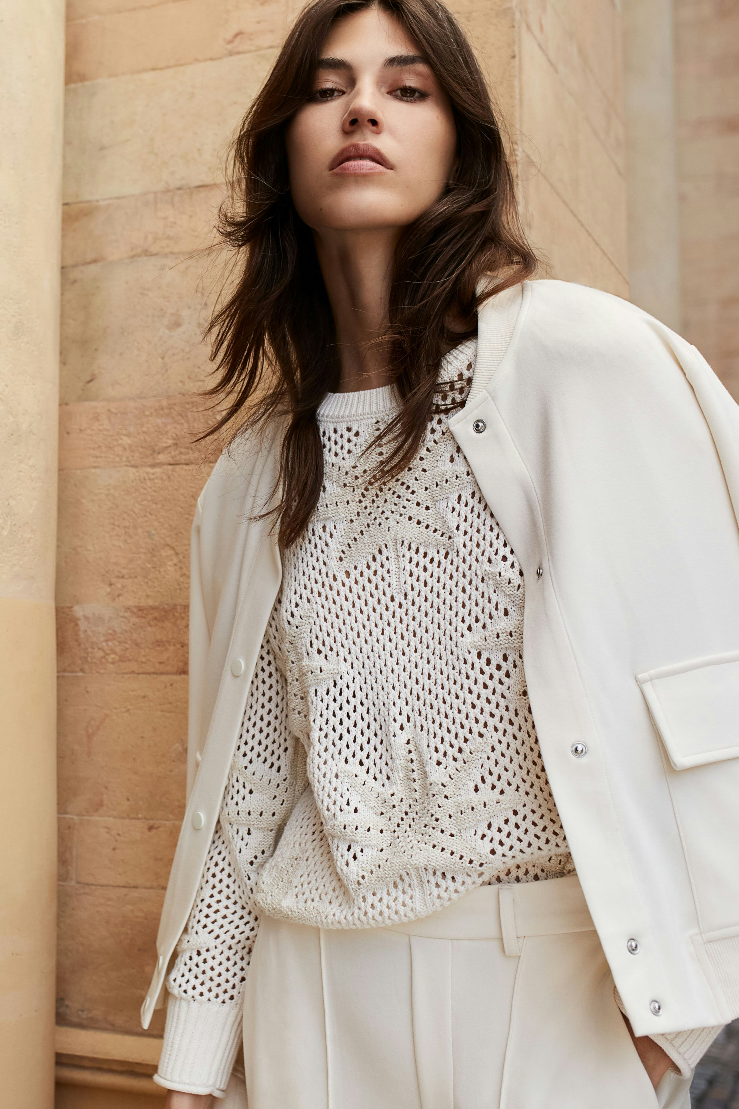 Eleganter Blouson: Frau in heller Bomberjacke kombiniert mit lässigem Outfit vor historischer Kulisse.