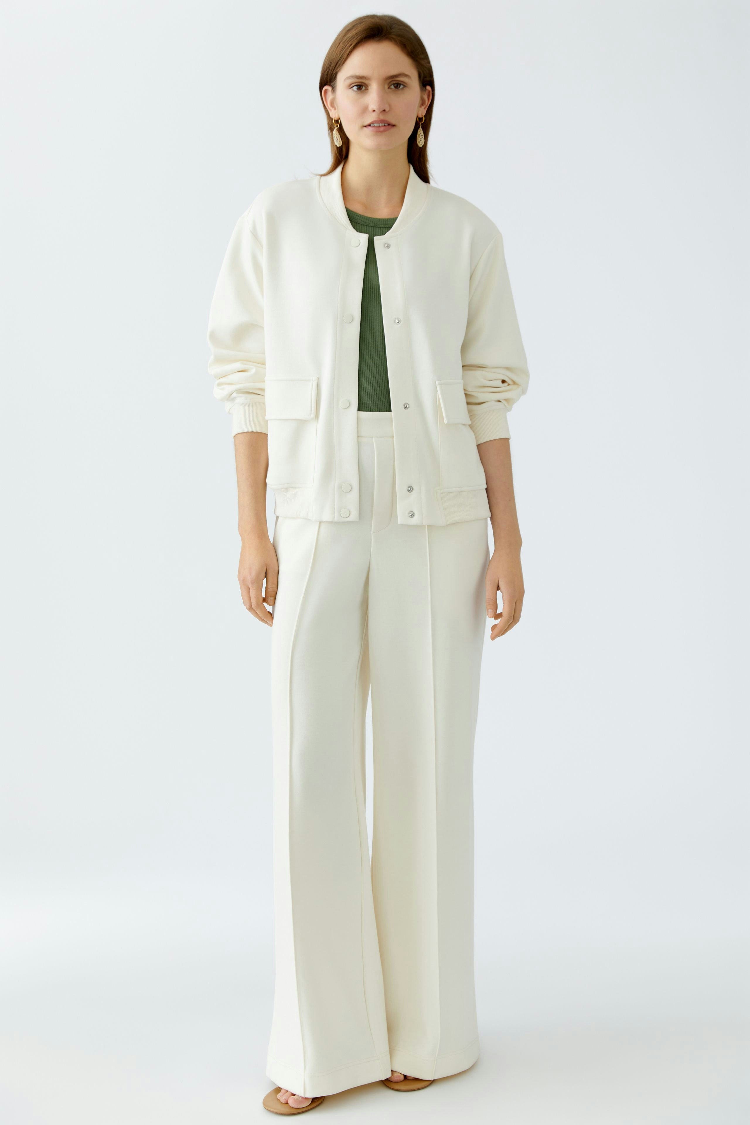 Eleganter Blouson: Frau in cremefarbener Bomberjacke mit lässigen Details und weiten Hosen.