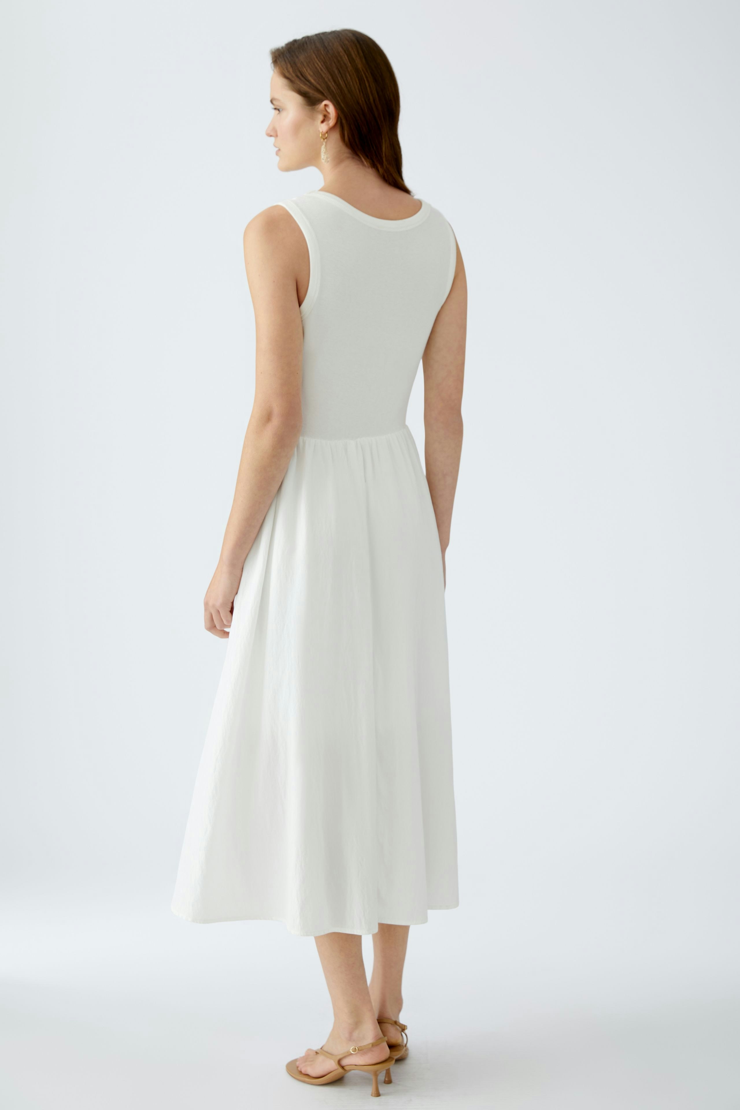 Elegant white dress: A woman in a sleeveless, flowing white dress, showcasing a chic and timeless style.