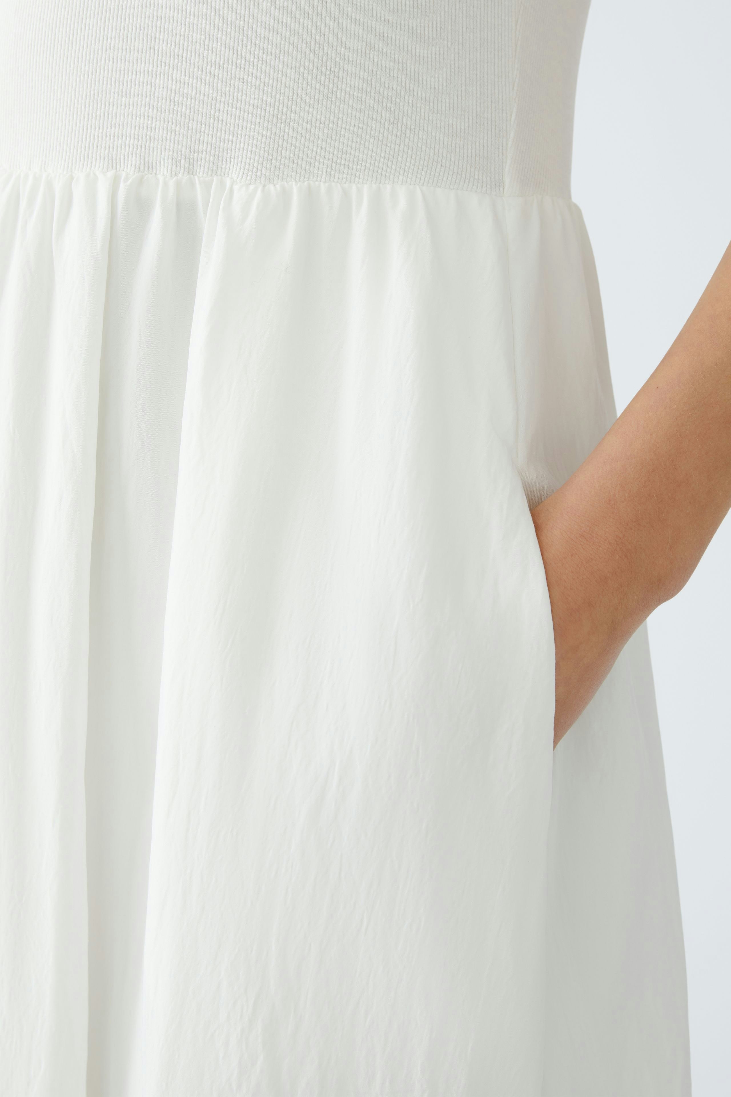 Elegant white dress: A woman showcases a flowing design with pockets, perfect for any occasion.