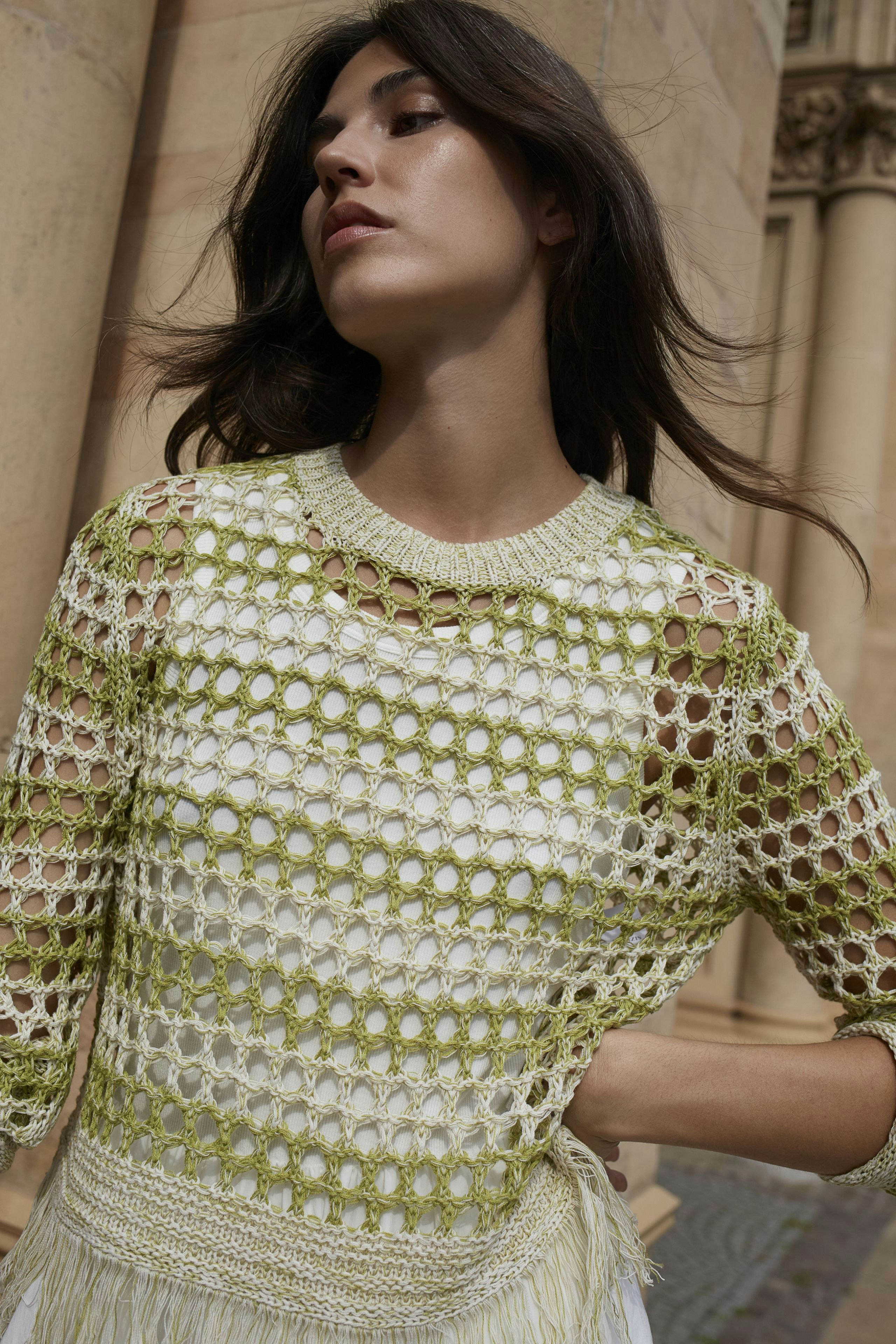 Stylish dress: A woman in a light green crochet dress with a relaxed fit, showcasing a modern design.