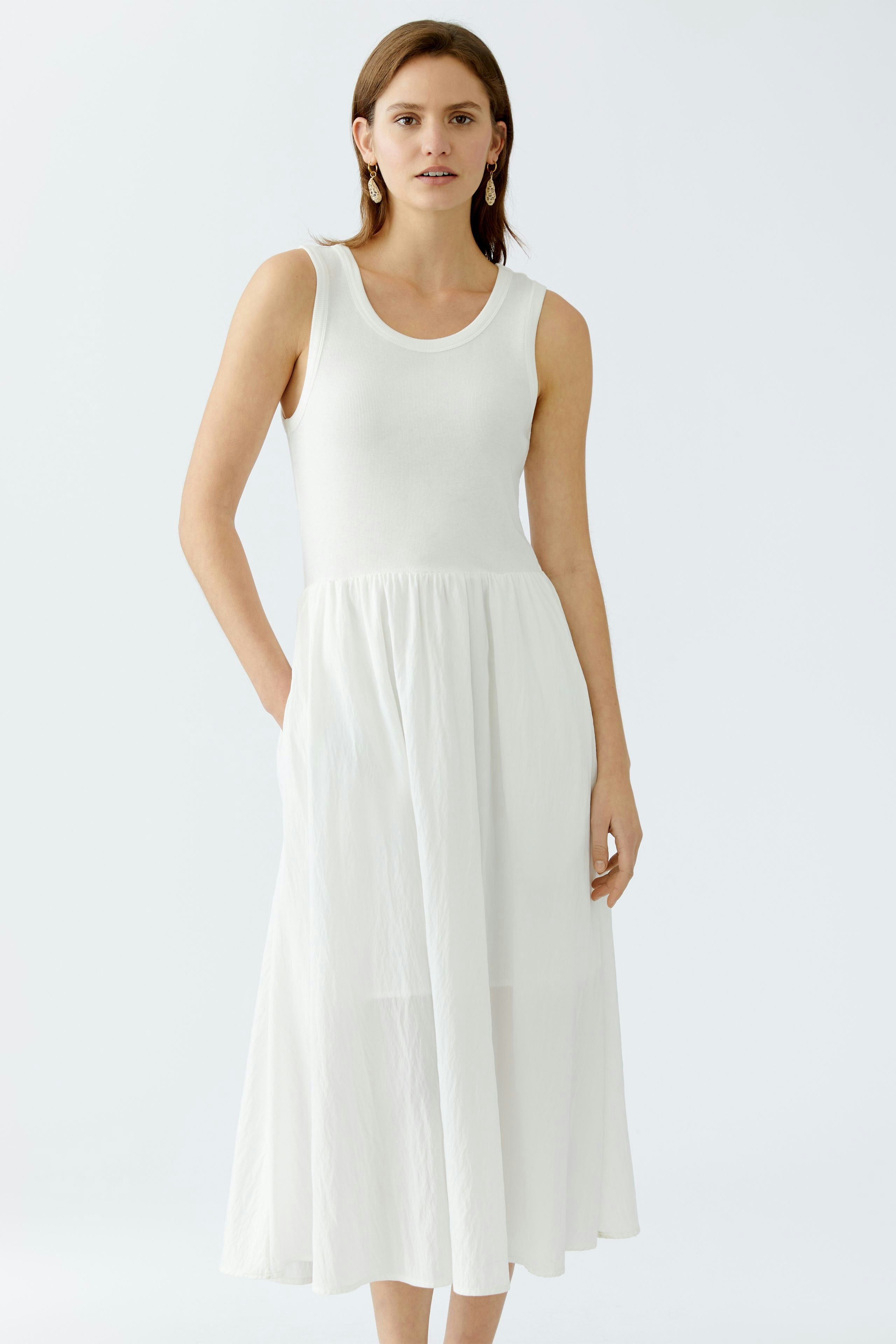 Elegant women's dress: A woman in a white sleeveless dress with a flowing skirt, exuding effortless style.