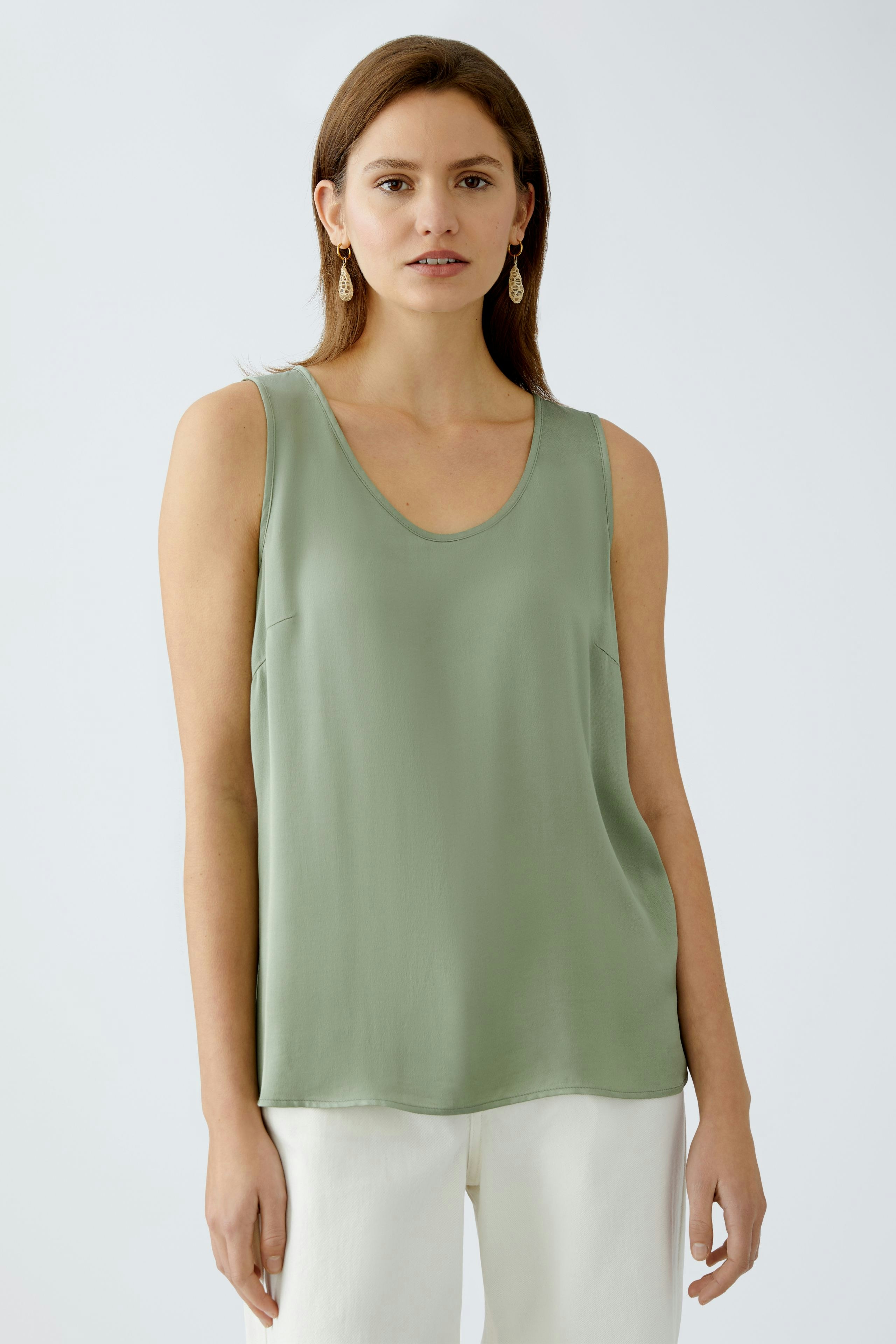 Elegantes Damen-Top: Frau trägt ein grünes, ärmelloses Top mit sanftem Fall und lässigem Schnitt.