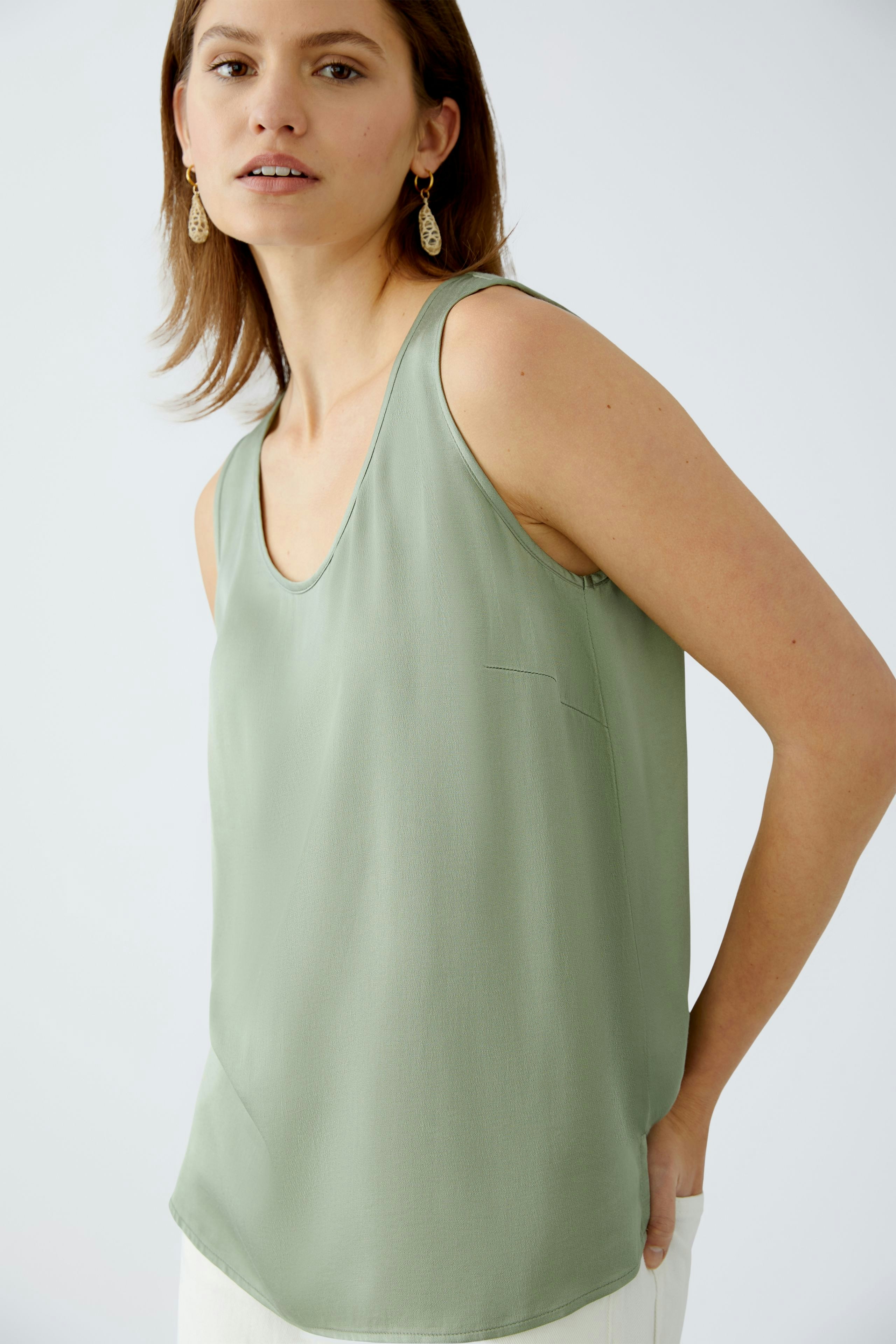 Elegantes Damen-Top: Frau trägt ein leichtes, mintgrünes Top mit schmalen Trägern und lässigem Schnitt.