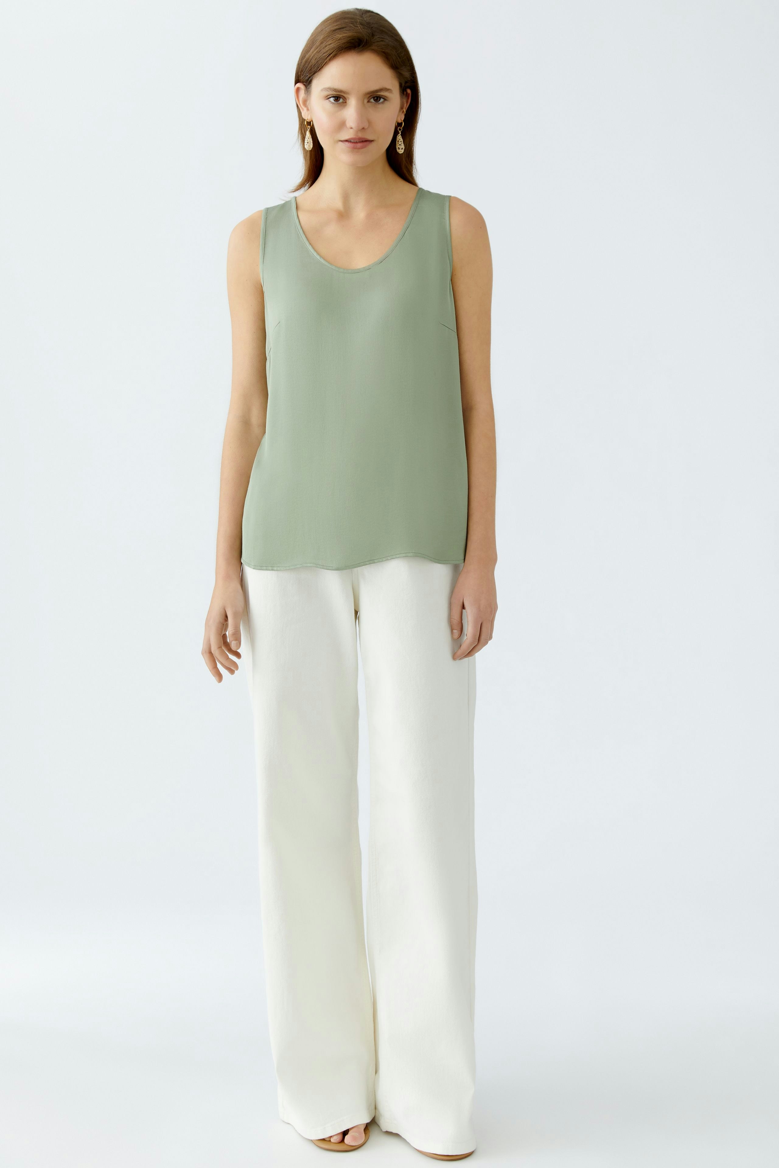 Elegantes Damen-Top in sanftem Grün, lässig kombiniert mit weißen, weiten Hosen.
