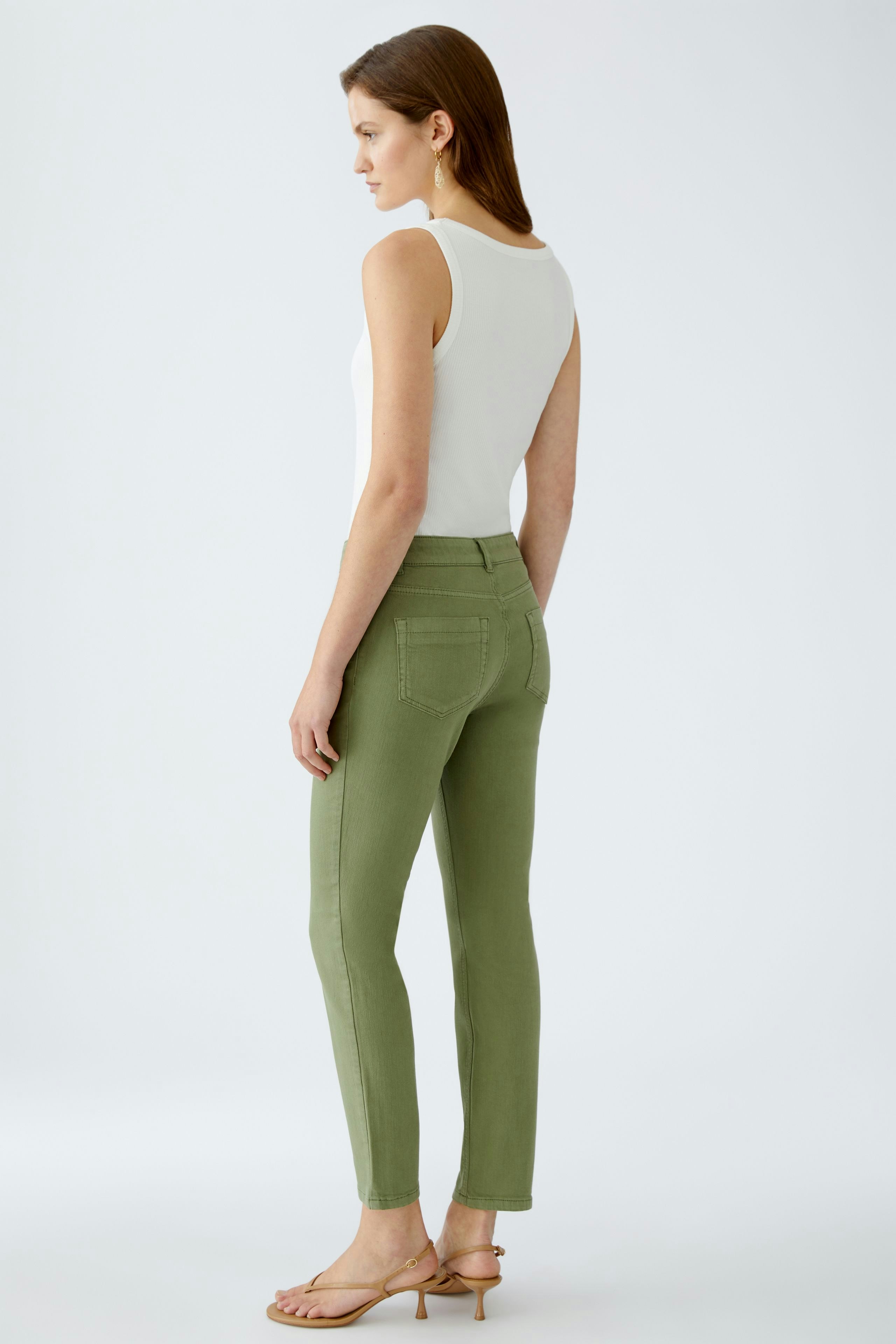 Damen-Jeggings: Frau in olivgrünen Jeggings mit figurbetontem Schnitt und lässigem Oberteil.