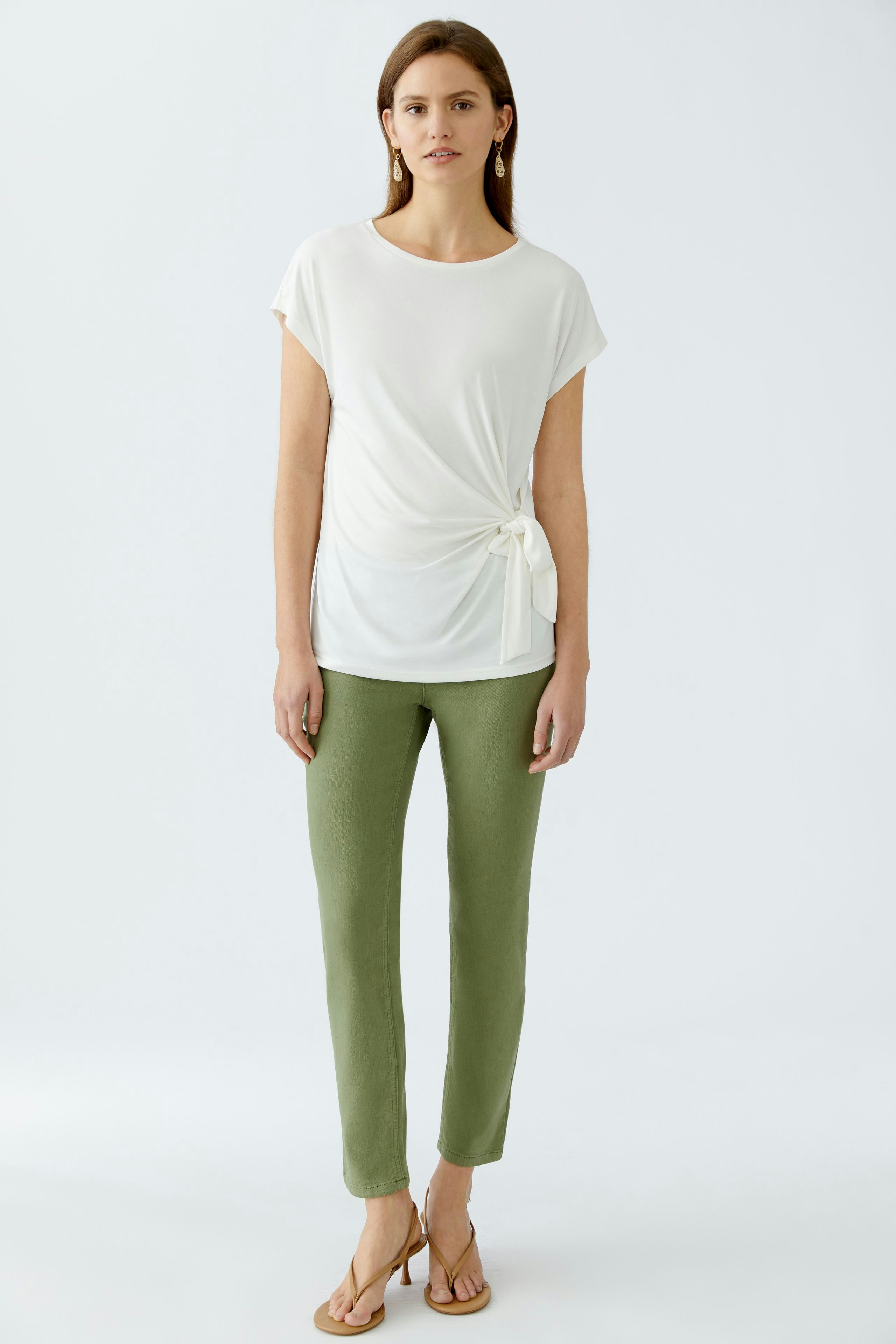 Moderne Jeggings: Junge Frau in eleganten, grünen Jeggings und lässigem, weißen Oberteil.