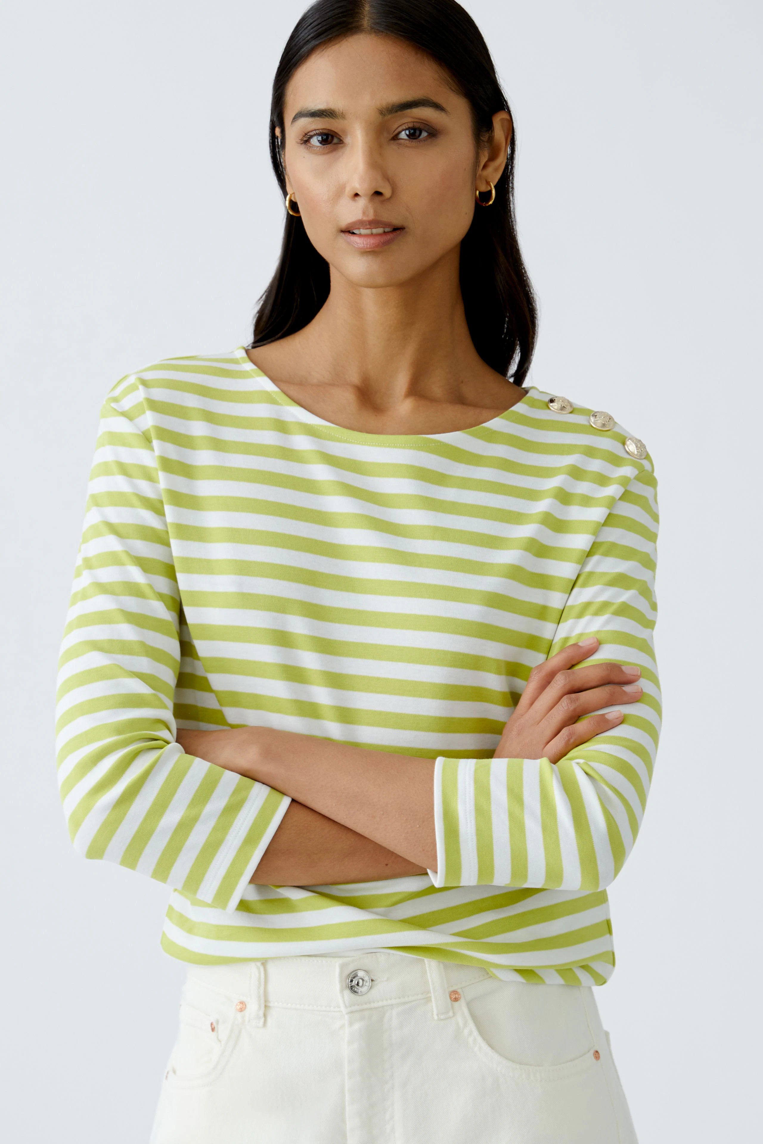 Damen Langarmshirt: Frau in gestreiftem Shirt mit Knöpfen an der Schulter, lässig und modern.