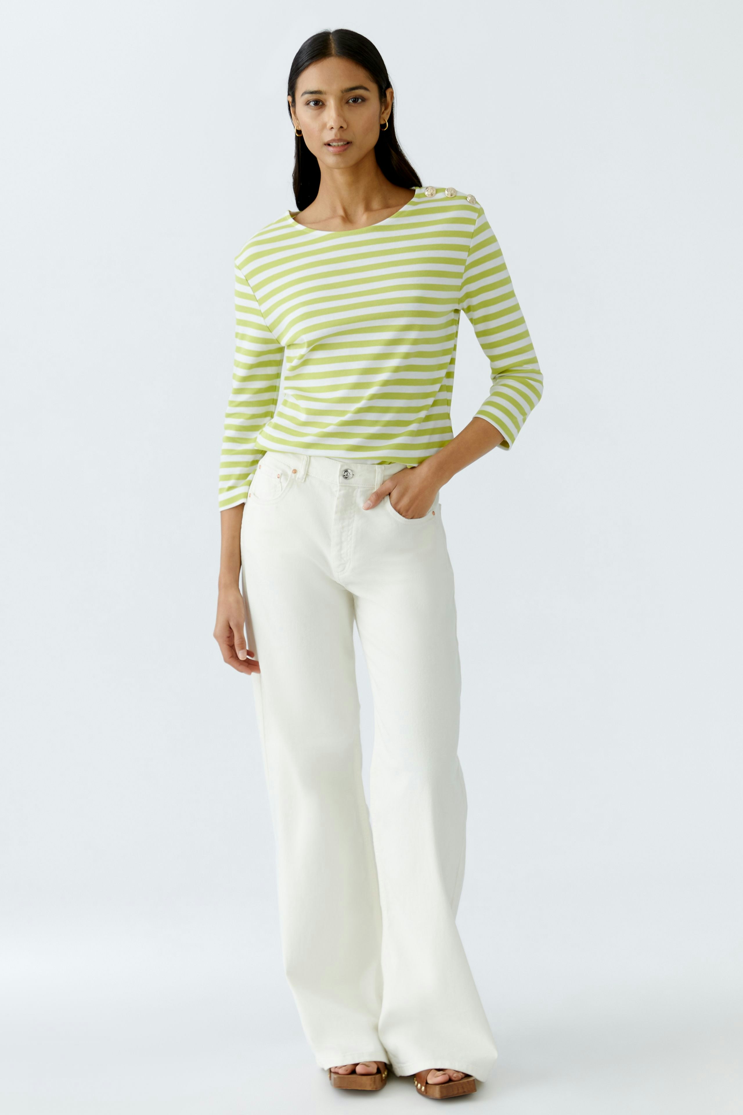 Stylish long-sleeve shirt: A woman in a green and white striped pullover, paired with white wide-leg pants.