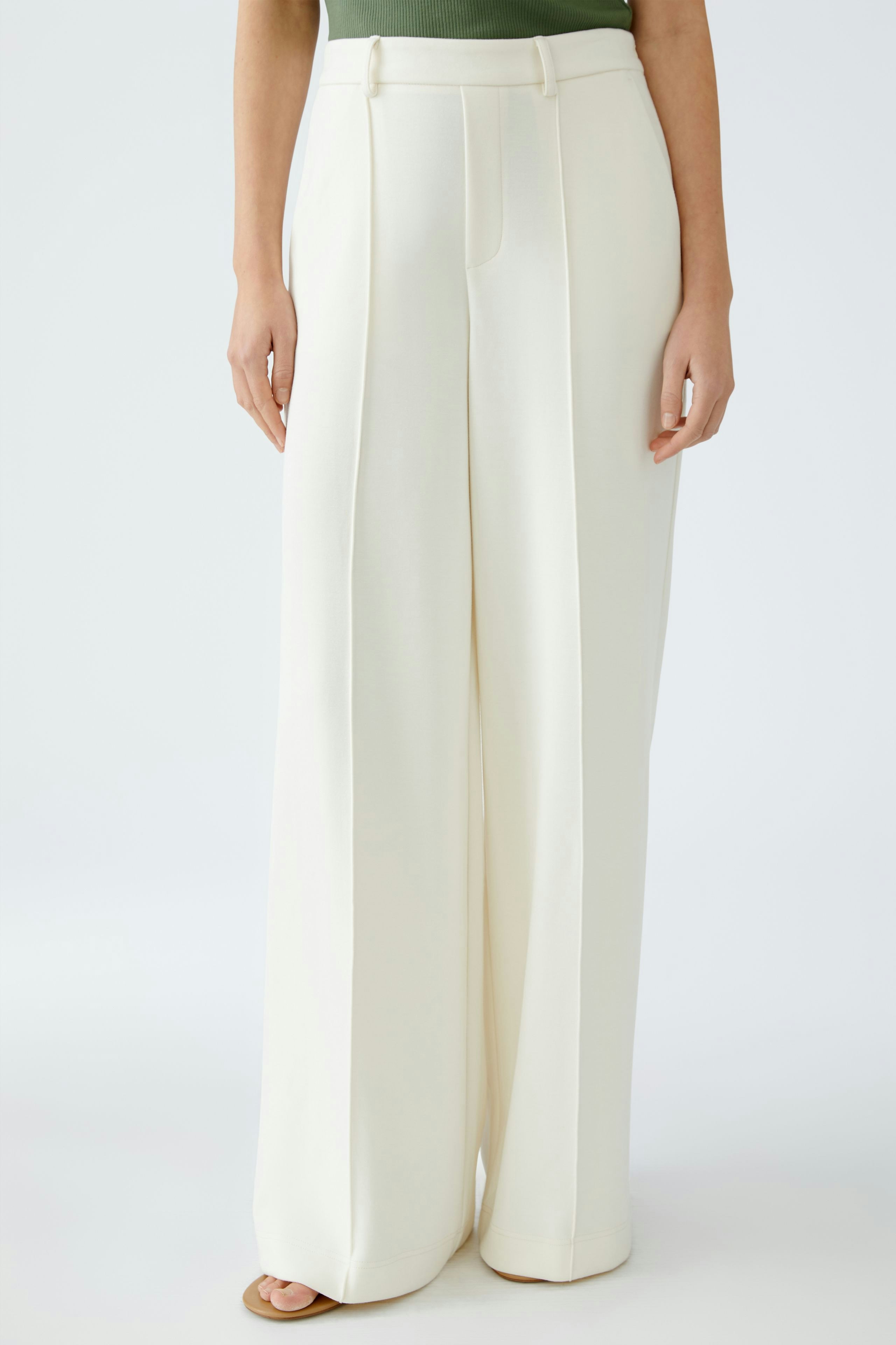 Elegant women's trousers: A woman in wide, cream-colored trousers with a tailored fit.