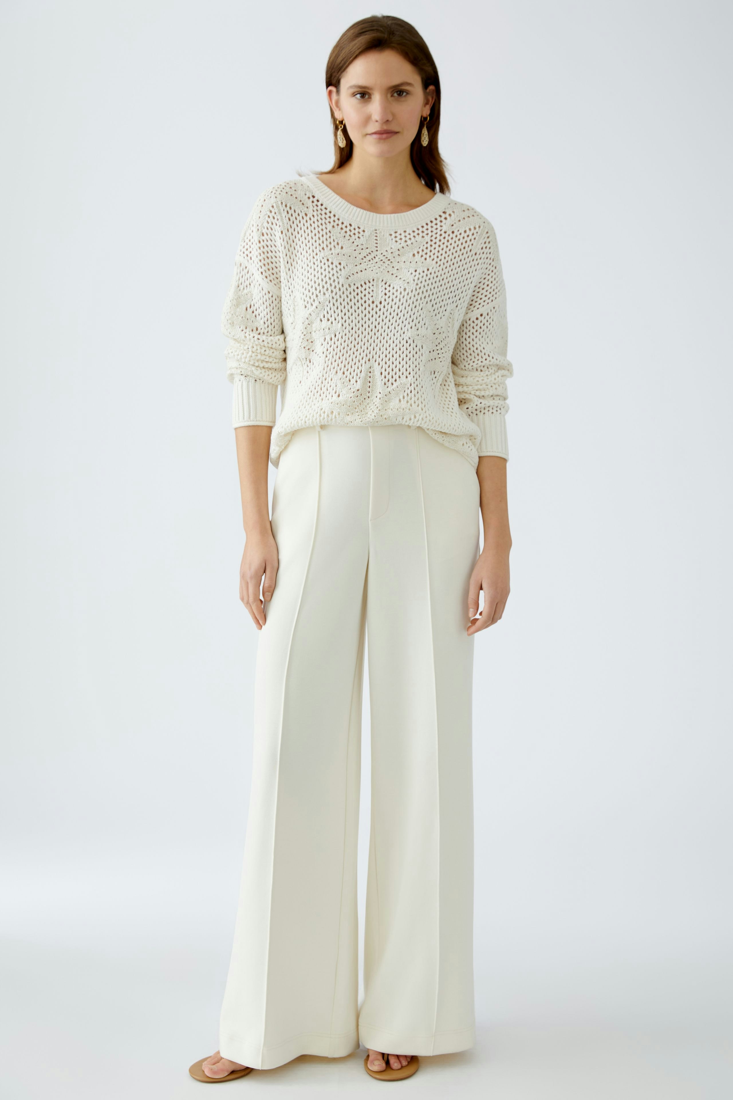 Elegant women's trousers: A woman in cream wide-leg trousers stands confidently against a light background.