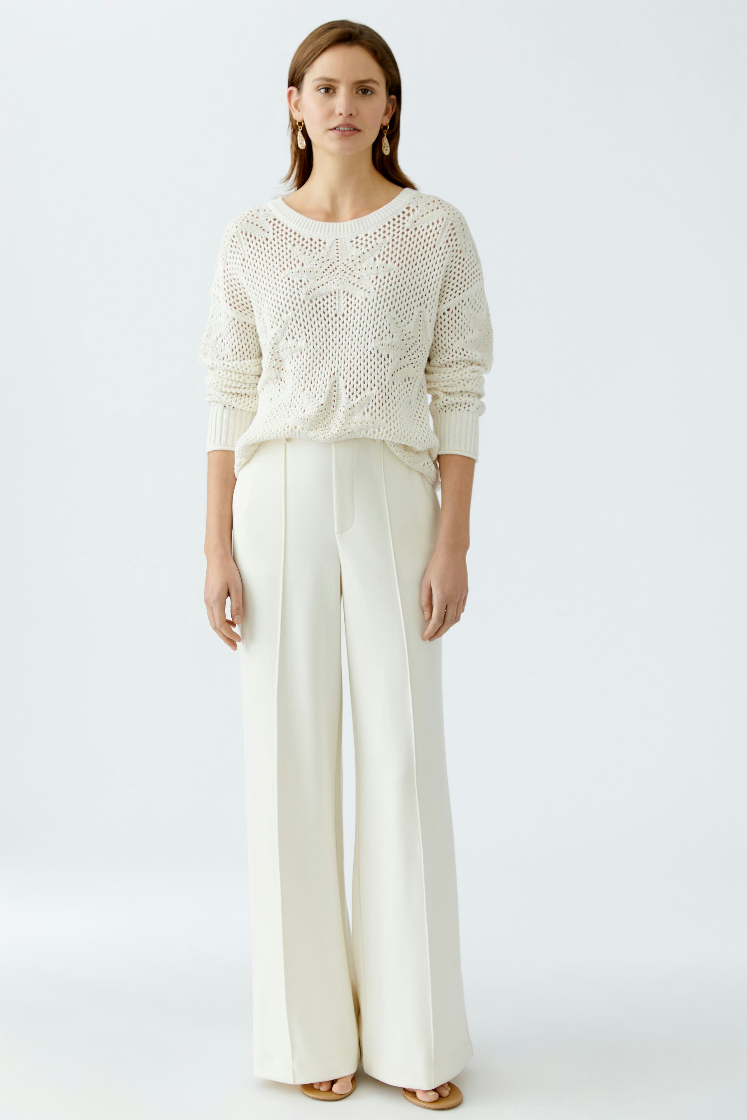 Elegant women's trousers: A woman in cream wide-leg trousers with pockets and a matching jacket.
