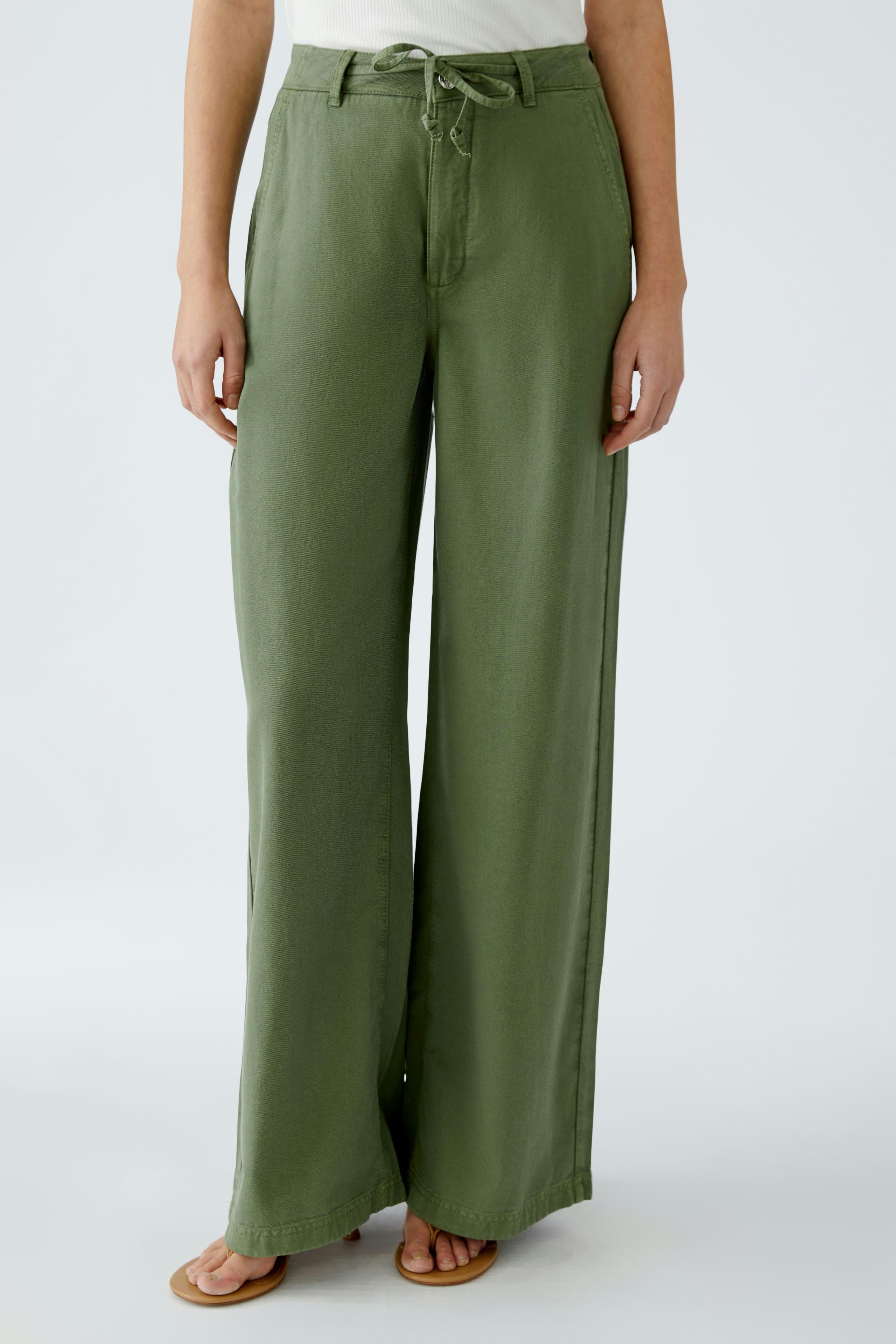 Stylish women's pants: A woman in loose-fitting green trousers with a drawstring waist.