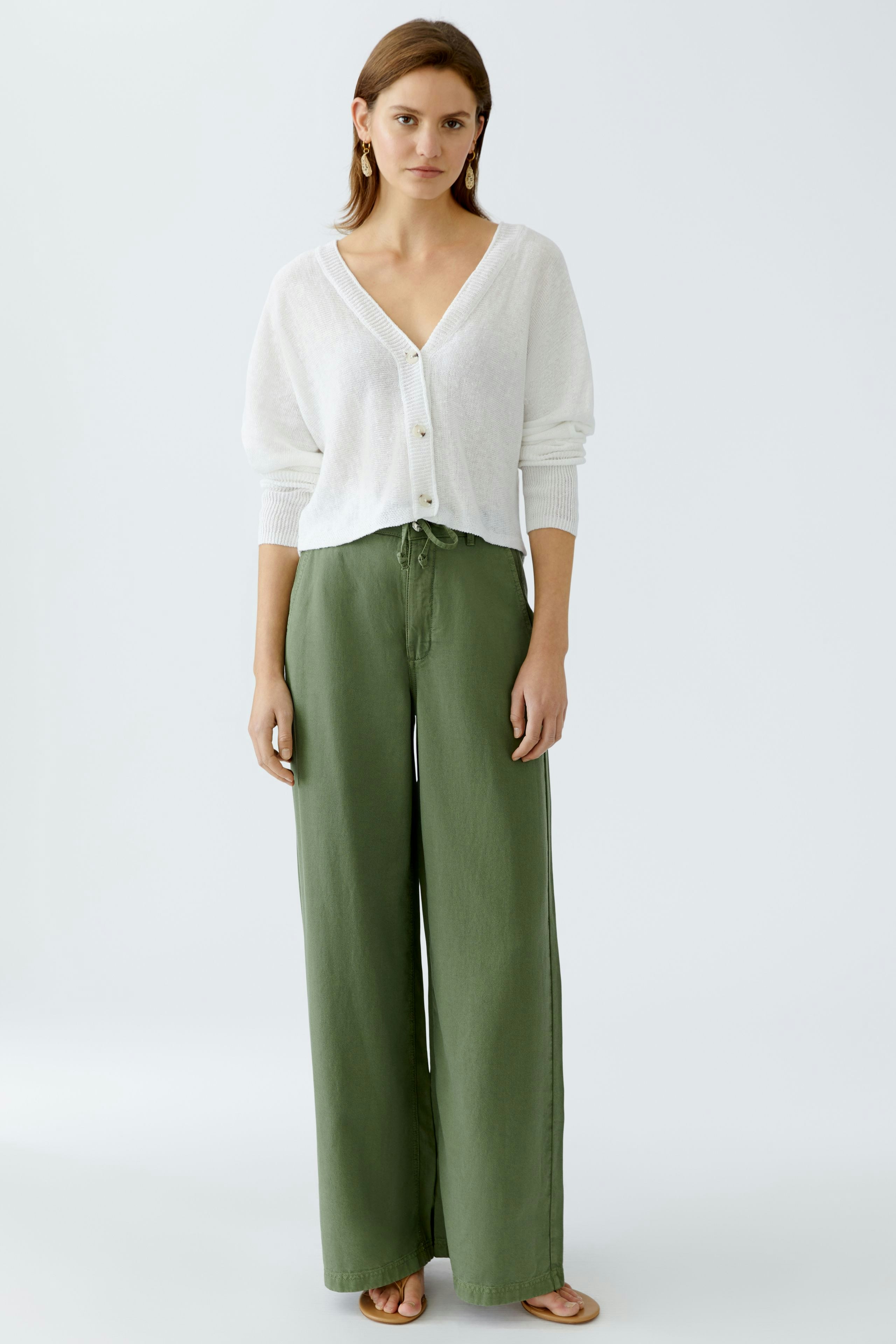 Stylish women's trousers: A woman in loose-fitting green pants with a relaxed fit.