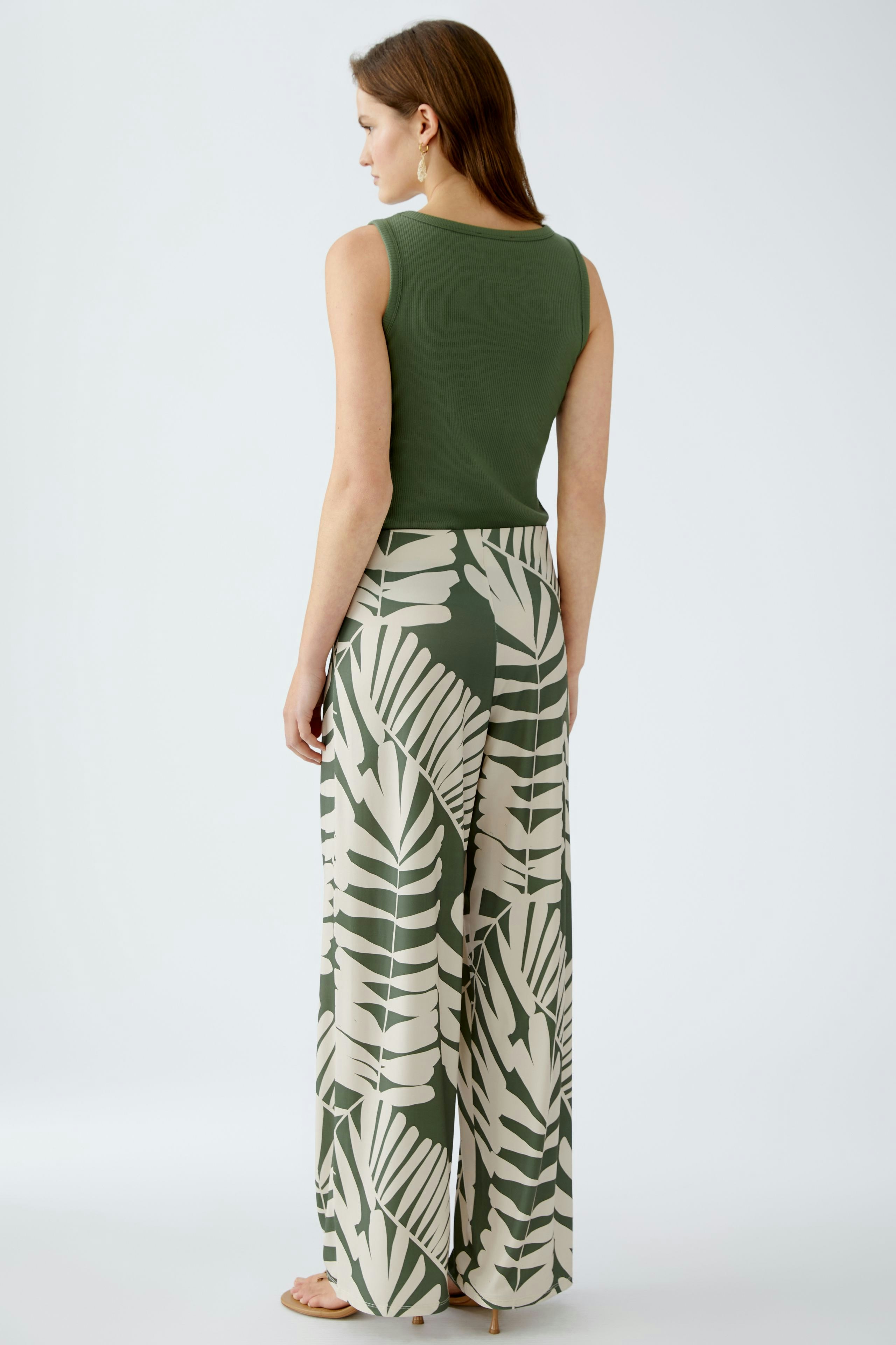 Luftige Damen-Hose: Frau trägt eine bequeme, gemusterte Hose mit floralem Design und weitem Schnitt.