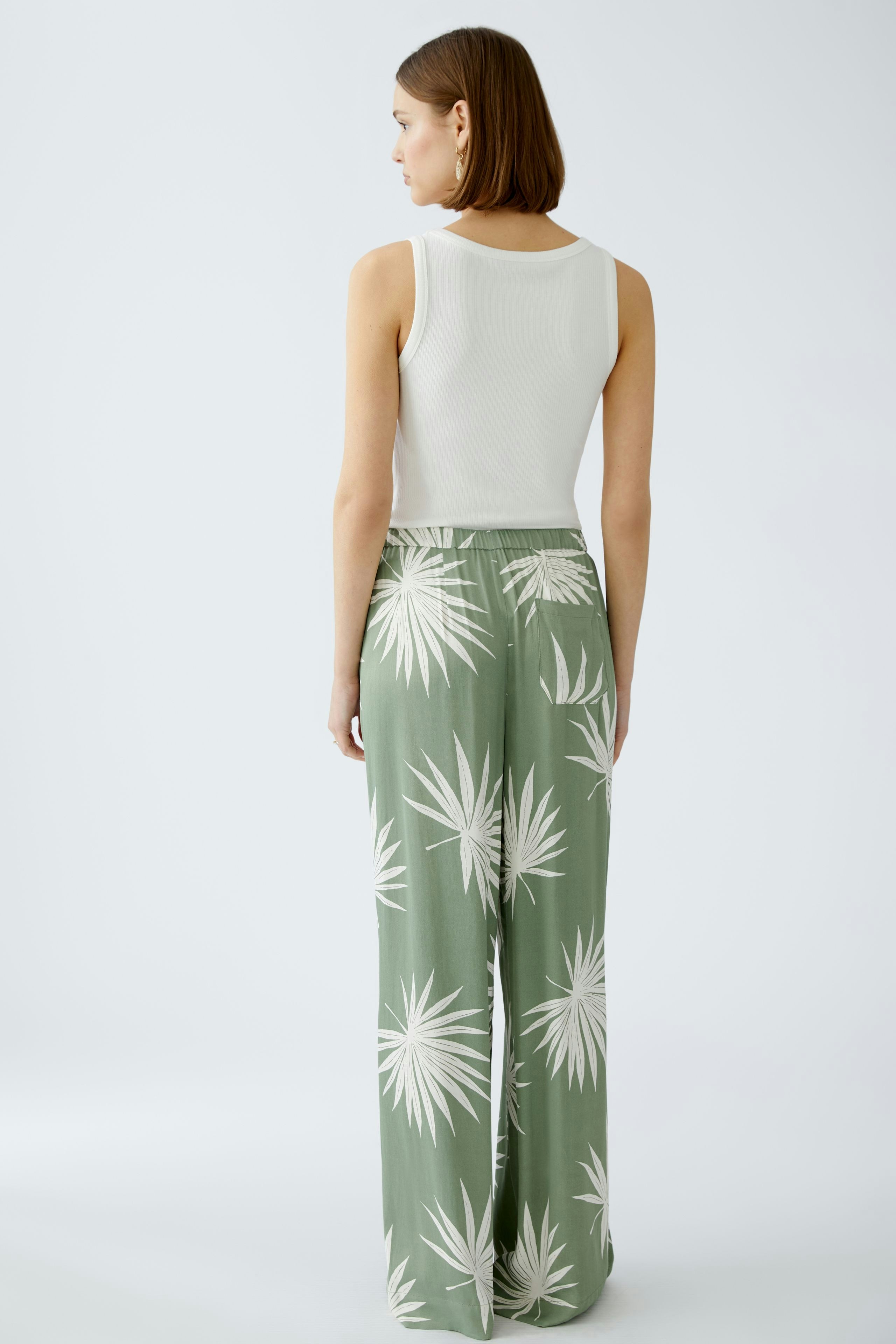 Luftige Damen-Hose: Frau in grüner Hose mit Pflanzenmuster, ideal für warme Tage.