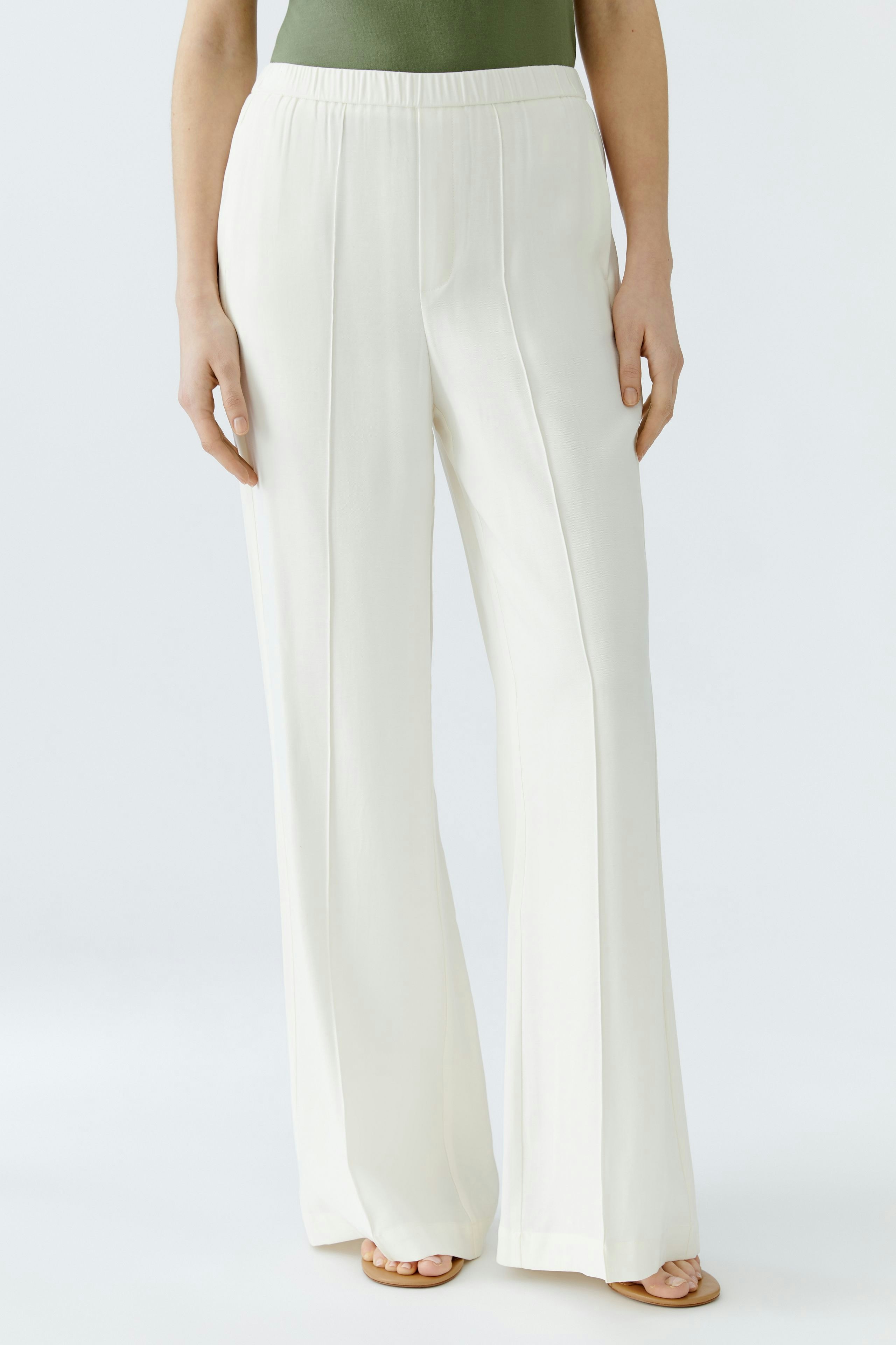 Elegant women's trousers: A woman in flowing white pants stands confidently against a light background.