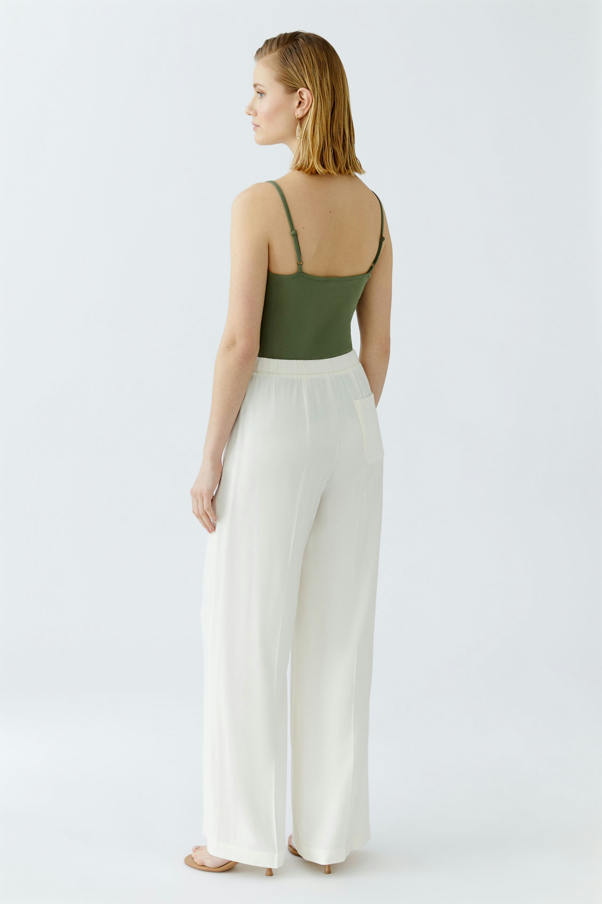 Elegant women's trousers: A woman in white wide-leg trousers, showcasing a chic and modern style.