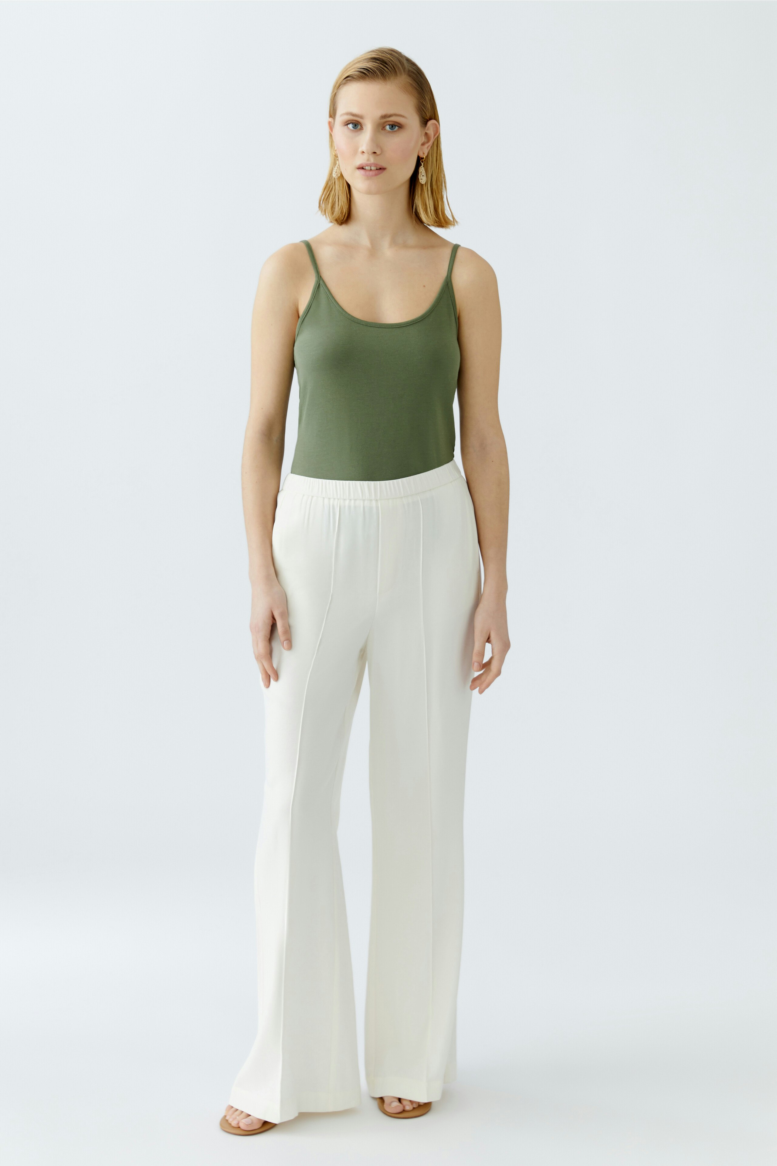 Elegant women's trousers: A woman in white, wide-leg trousers stands confidently against a light background.