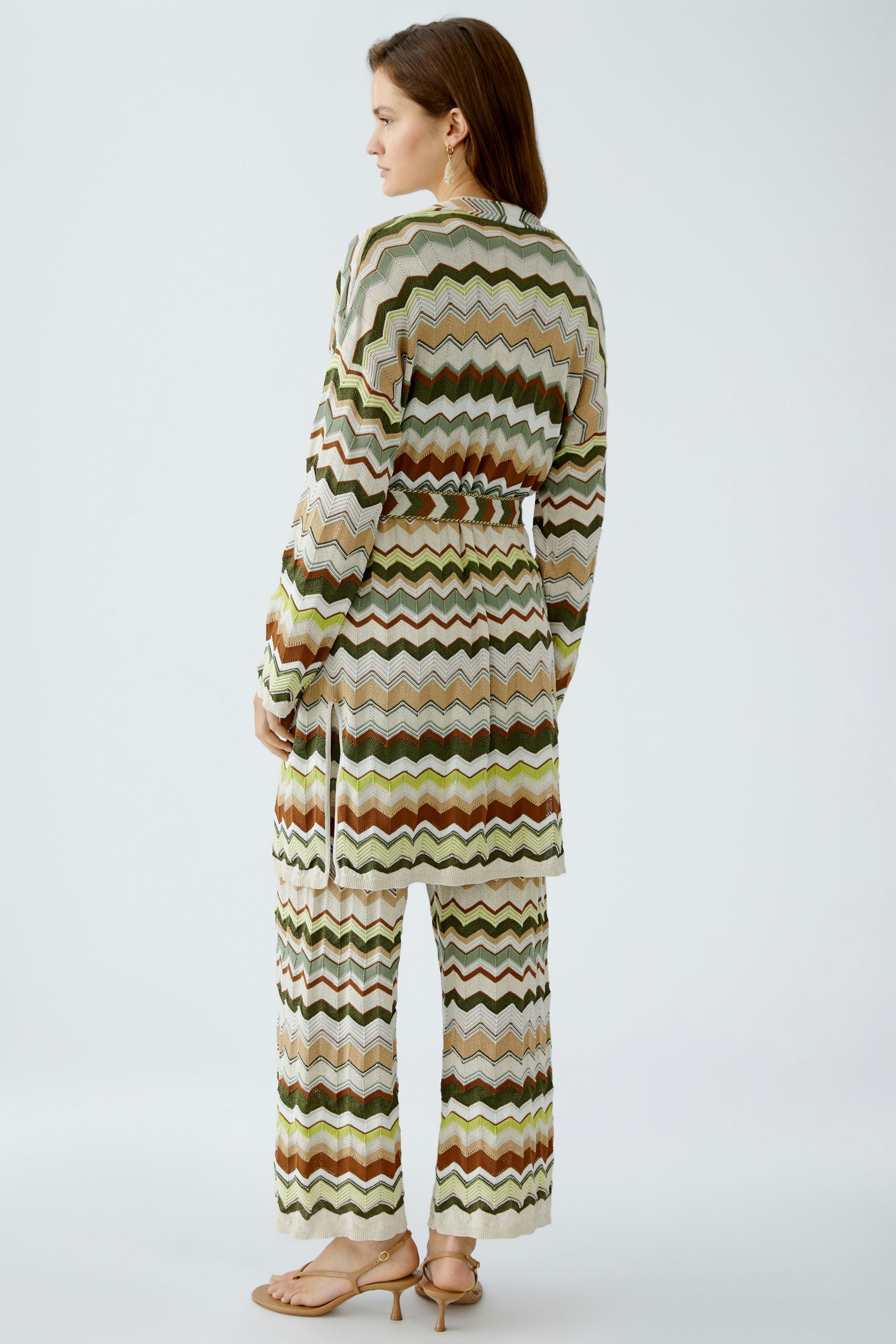 Stylish women's cardigan: A woman in a patterned knit cardigan with a belt, showcasing a chic look.