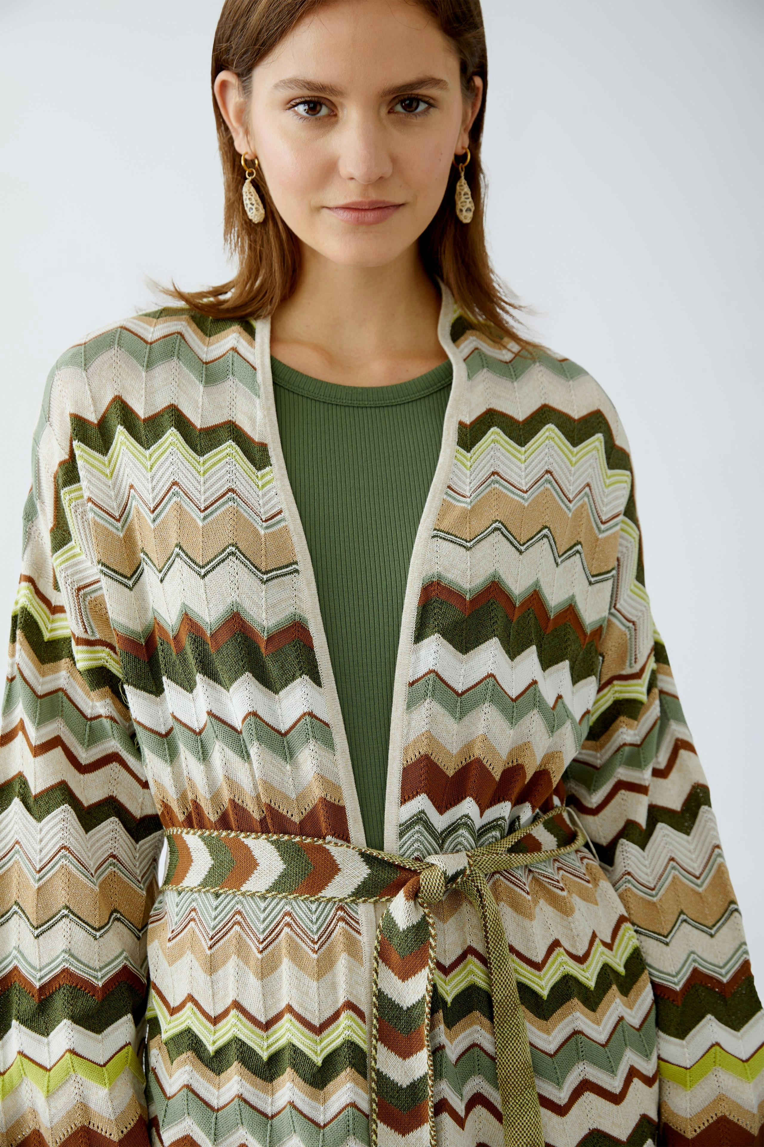 Stylish women's cardigan: A woman in a colorful zigzag-patterned knit cardigan with a belt.