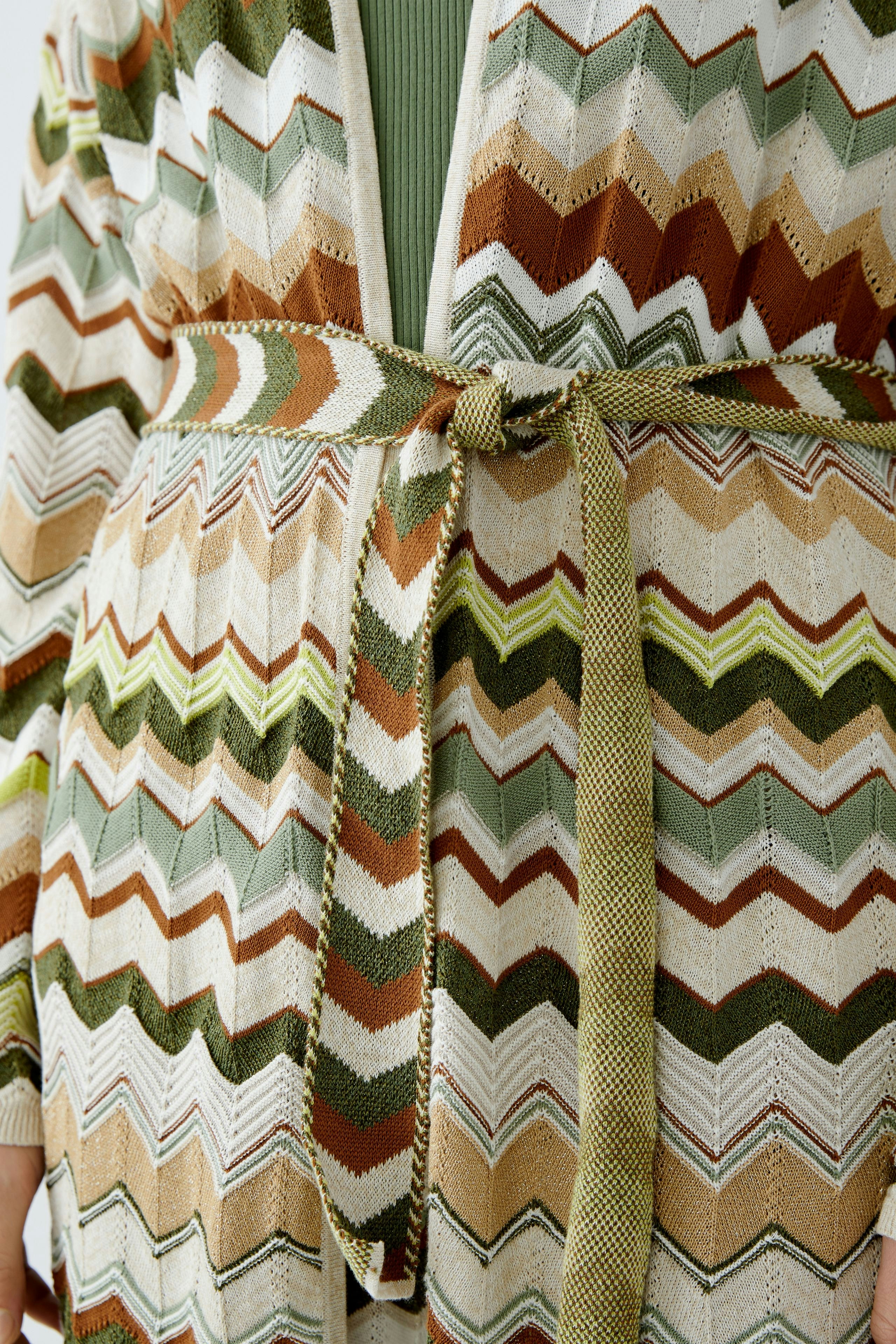 Stylish women's cardigan: A woman in a colorful zigzag-patterned knit cardigan with a belt.
