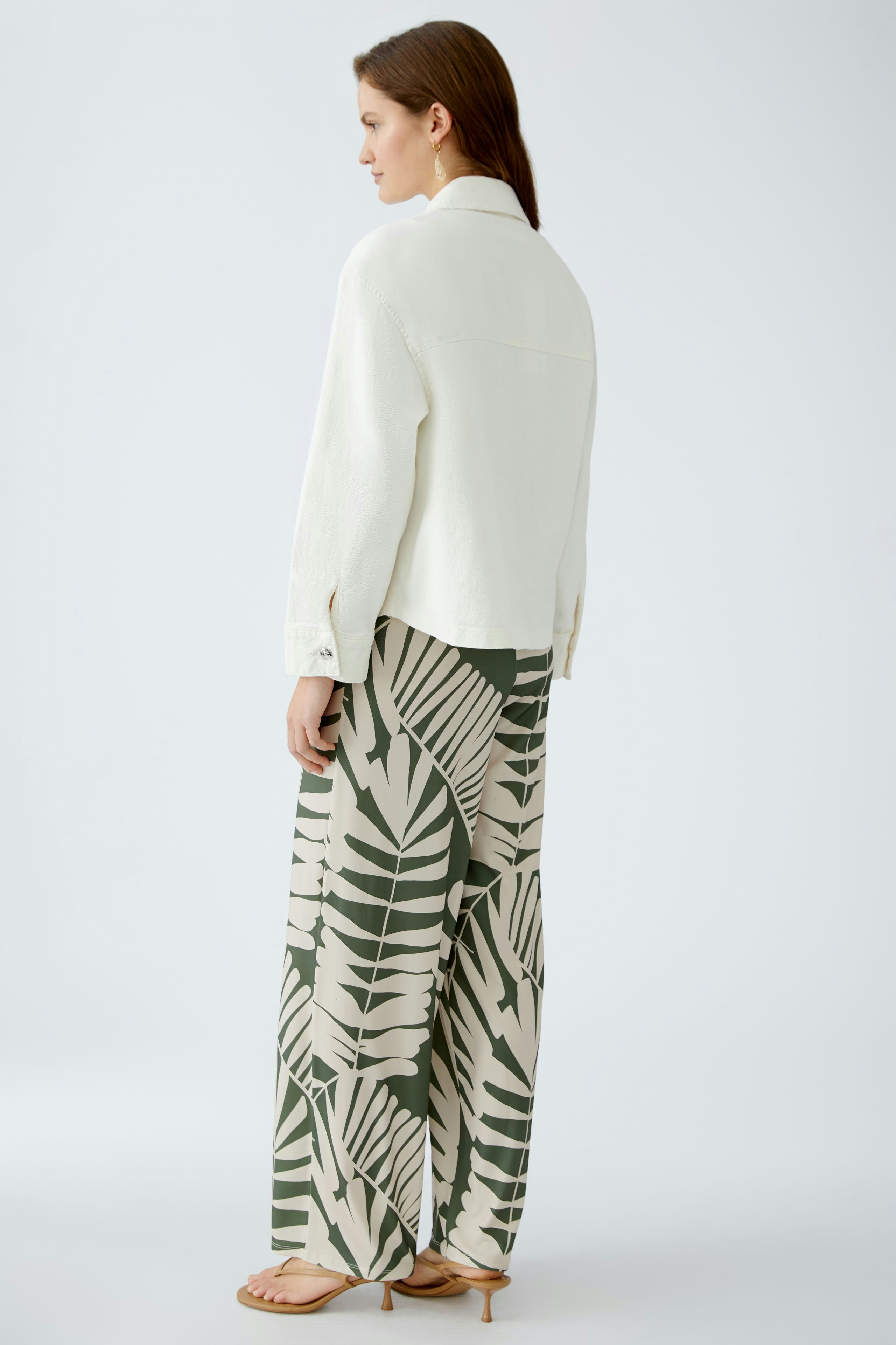 Stylish women's denim jacket: A woman in a white denim jacket paired with patterned wide-leg pants.