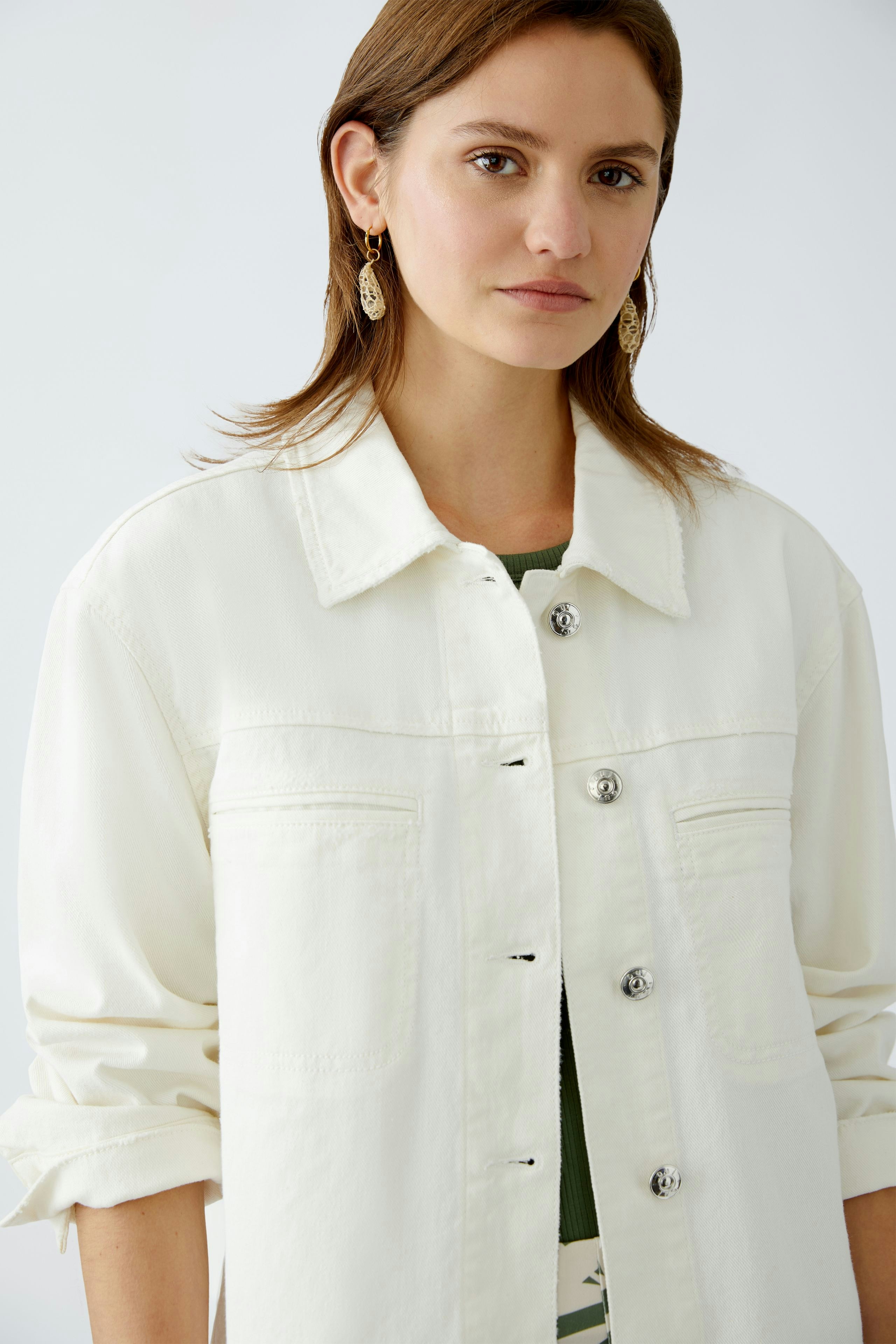 Stylish women's denim jacket: A woman in a white jacket with buttons, perfect for casual outfits.