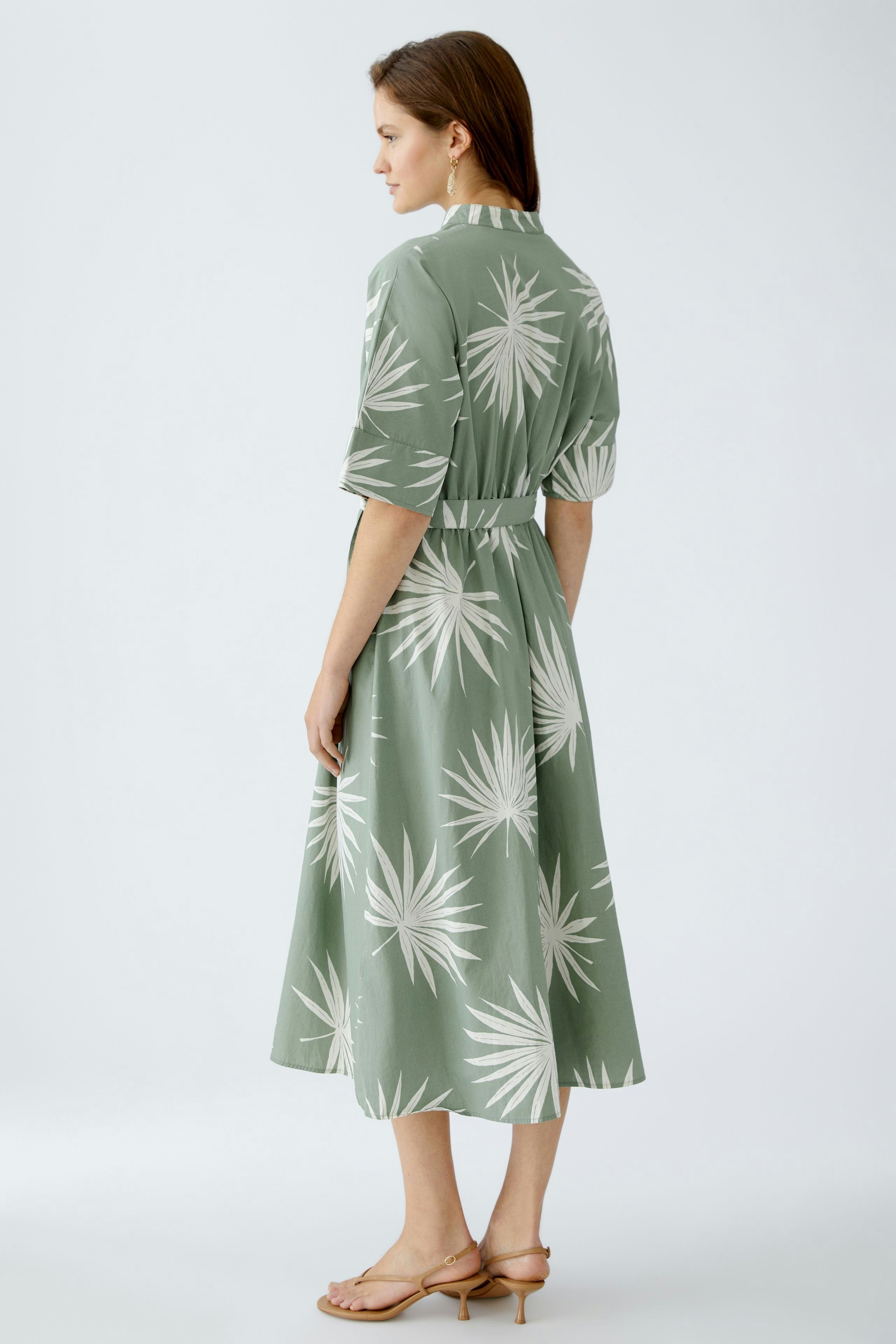 Elegantes Midikleid: Frau in grünem Kleid mit Blattmuster, lässig und stilvoll.