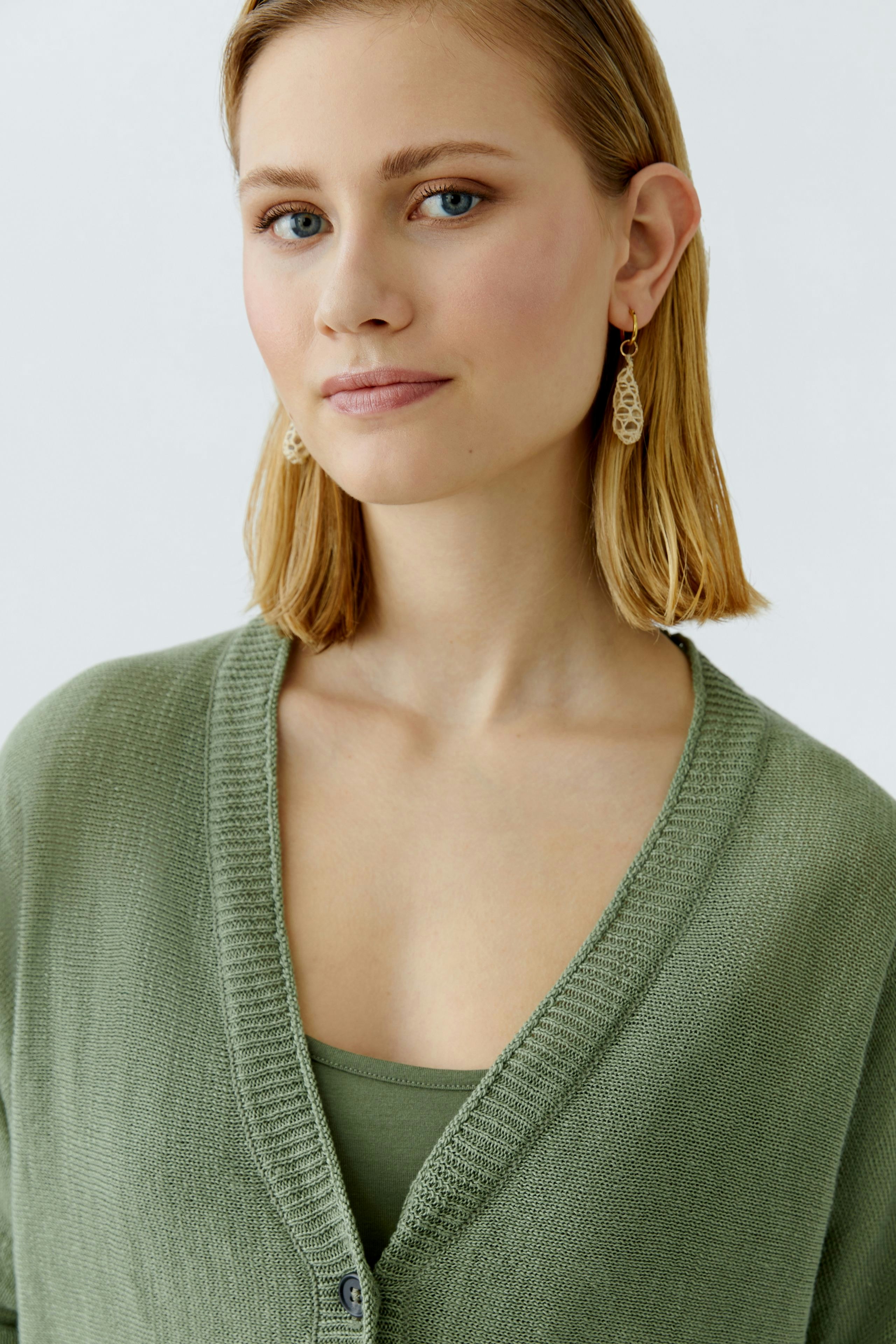 Elegante Damen-Strickjacke in sanftem Grün, lässig kombiniert mit einem Top.