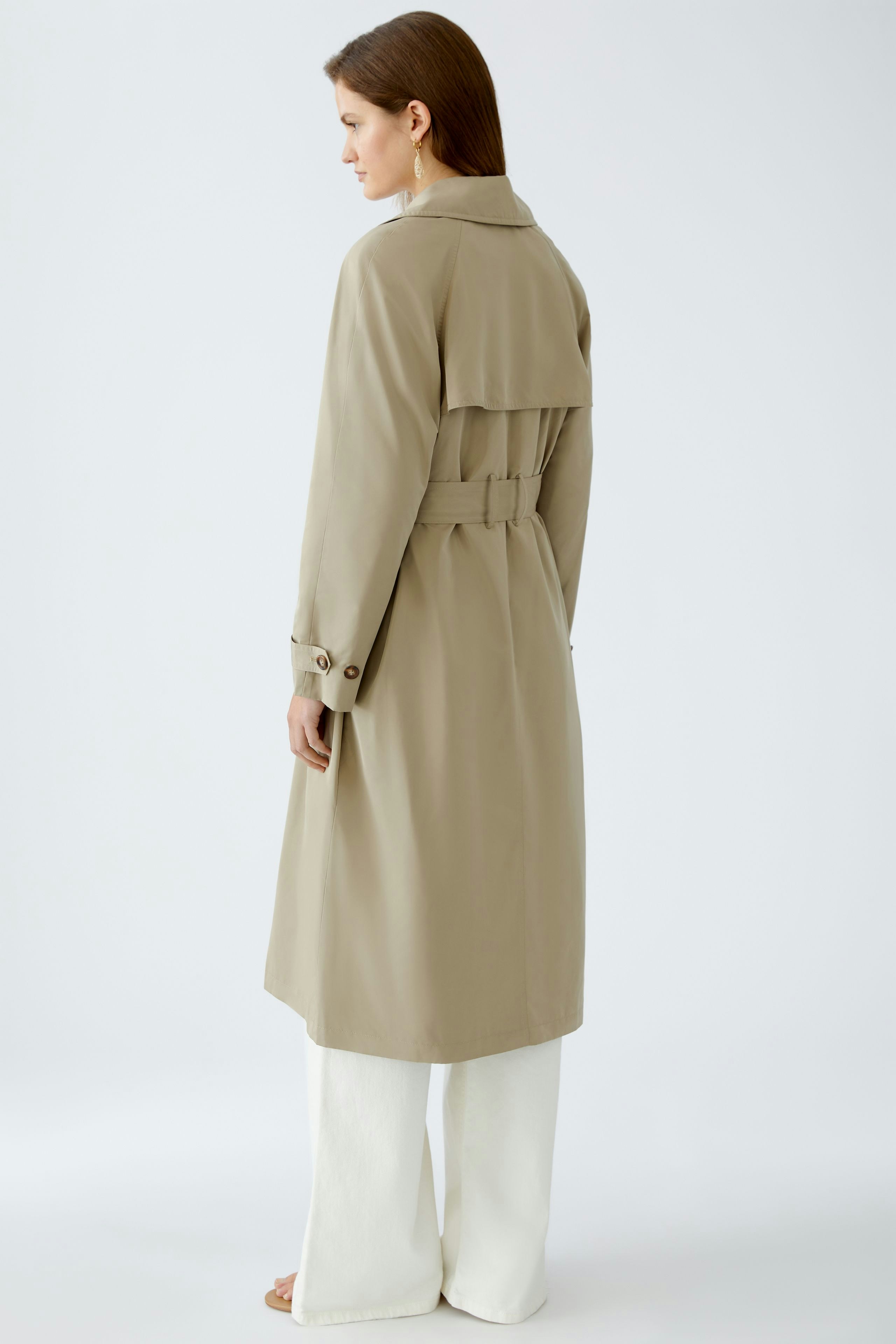Stylish trench coat: A woman in a beige trench coat with a belted waist and elegant design.